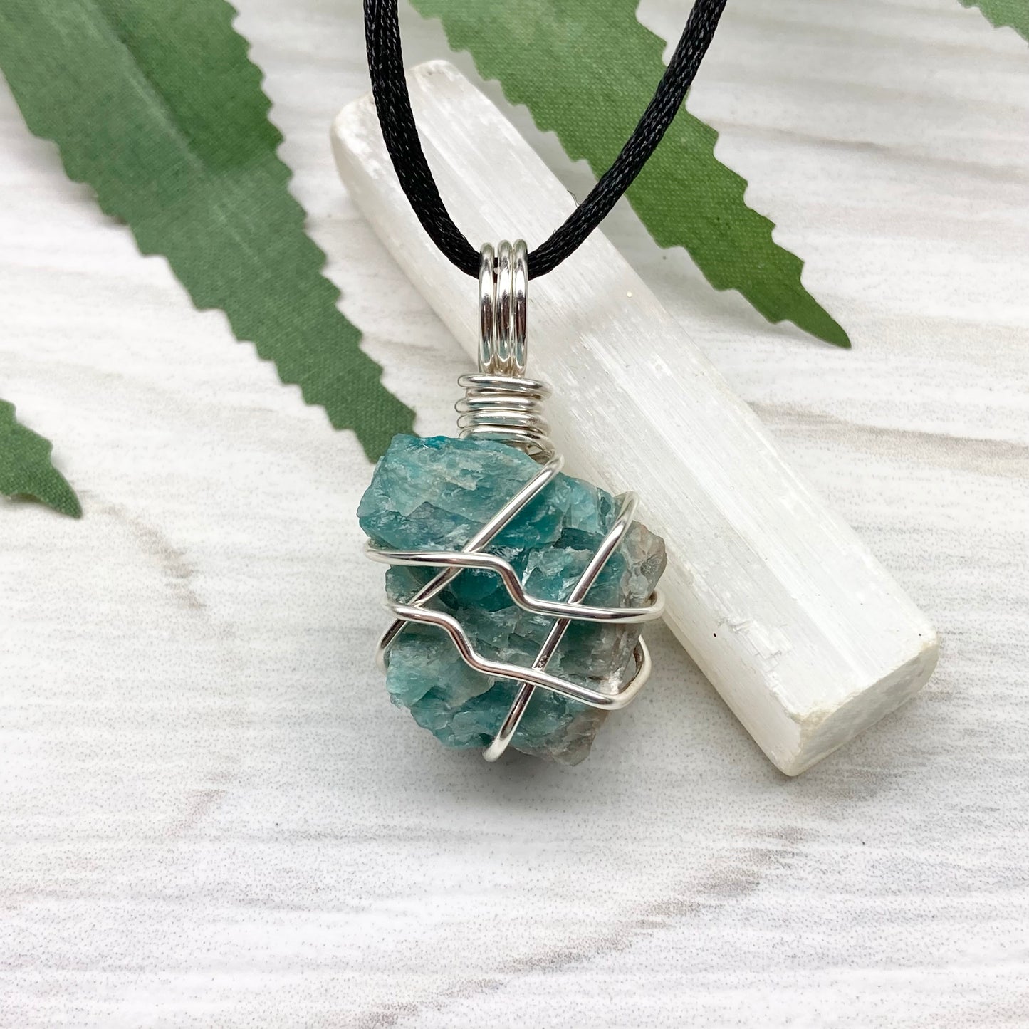 Blue Apatite necklace. Blue stone wrapped with silver copper wire. Hangs on a black chain.