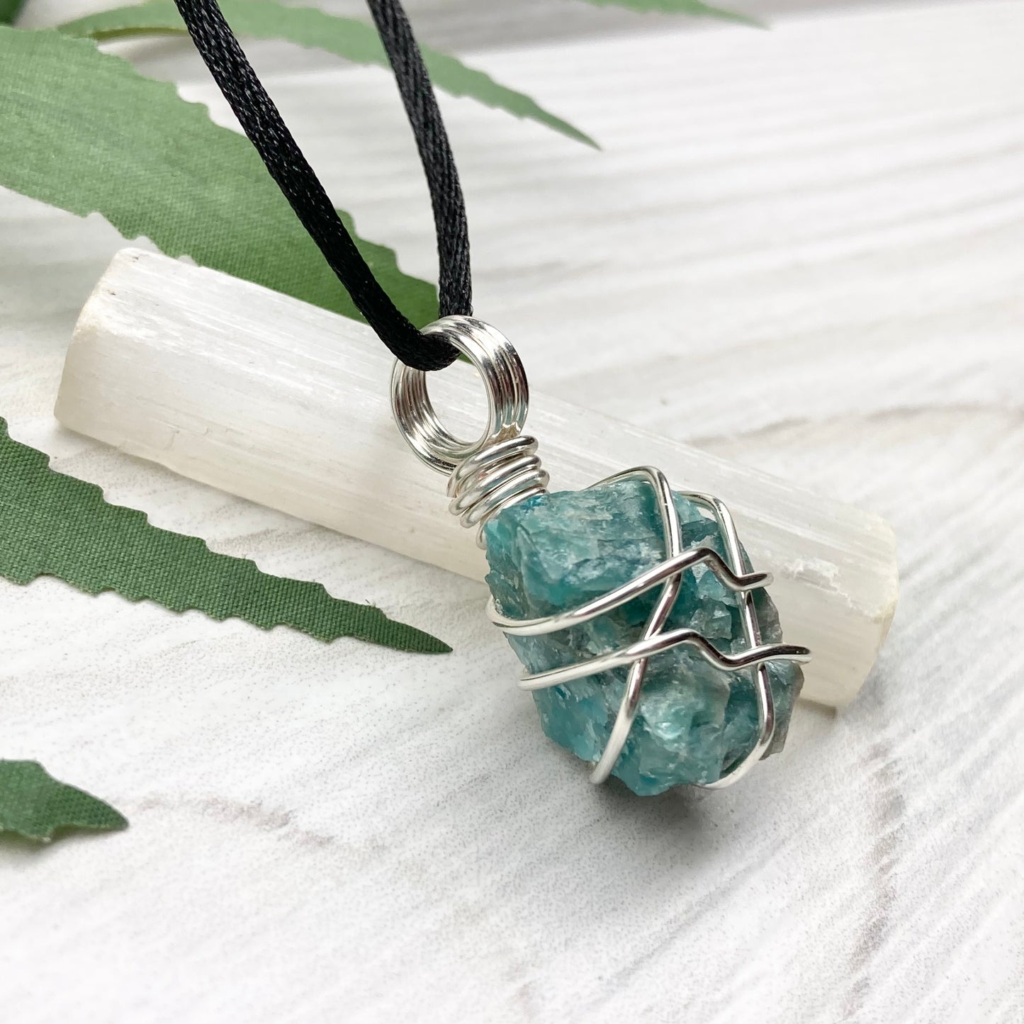Blue Apatite necklace. Blue stone wrapped with silver copper wire. Hangs on a black chain.