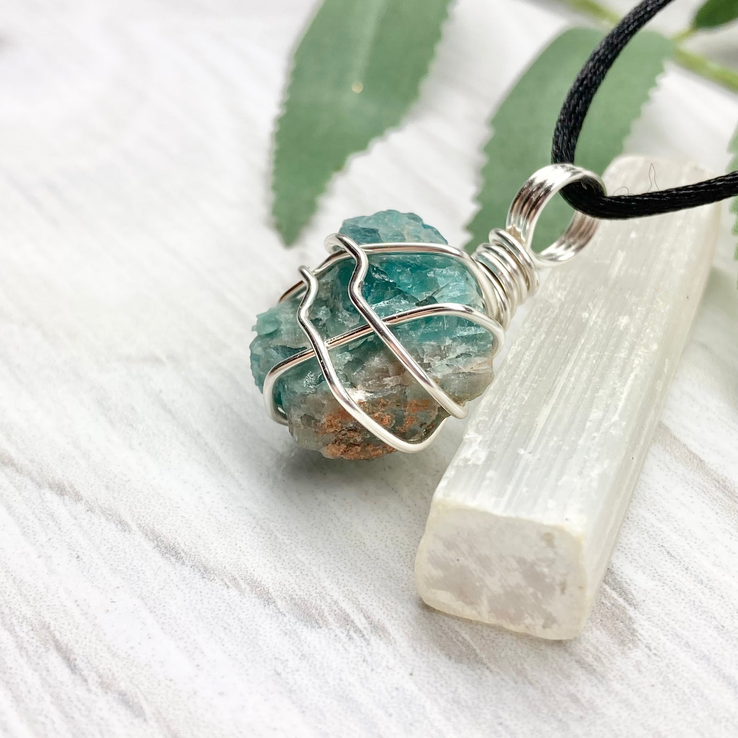 Blue Apatite necklace. Blue stone wrapped with silver copper wire. Hangs on a black chain.