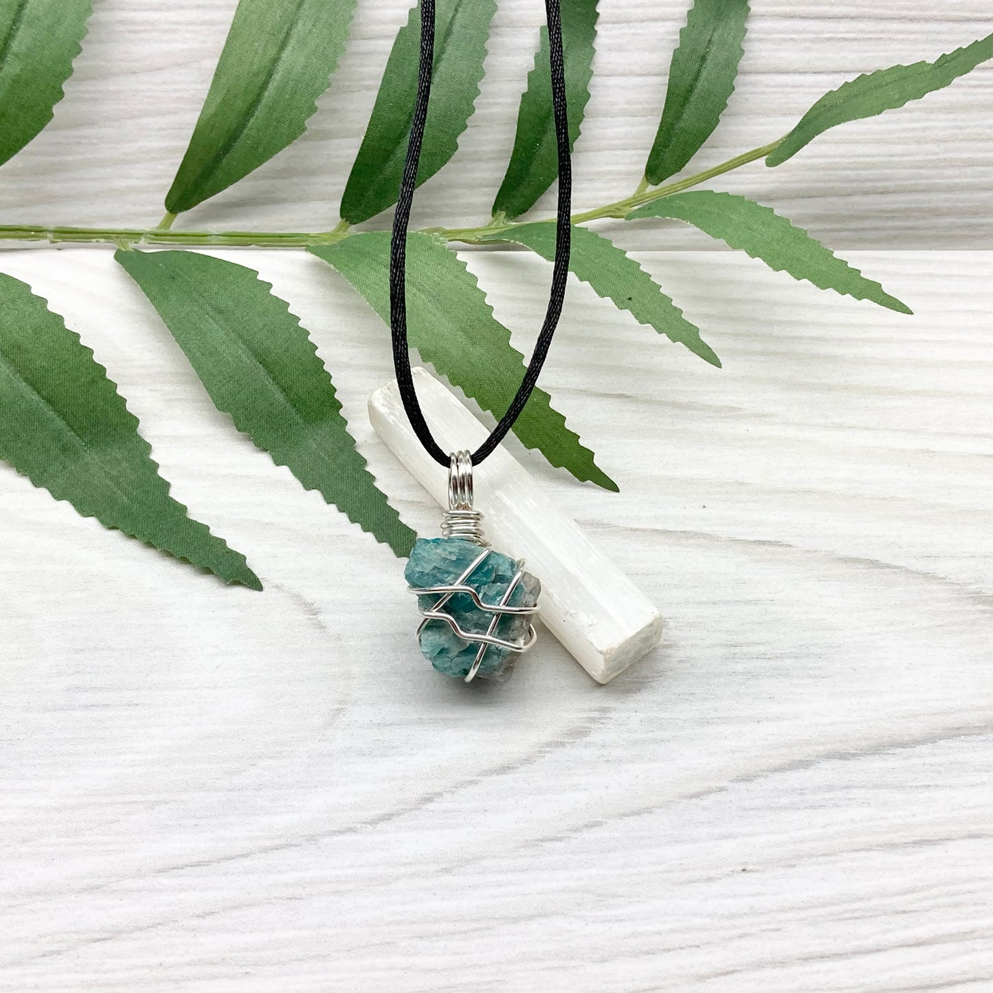 Blue Apatite necklace. Blue stone wrapped with silver copper wire. Hangs on a black chain.