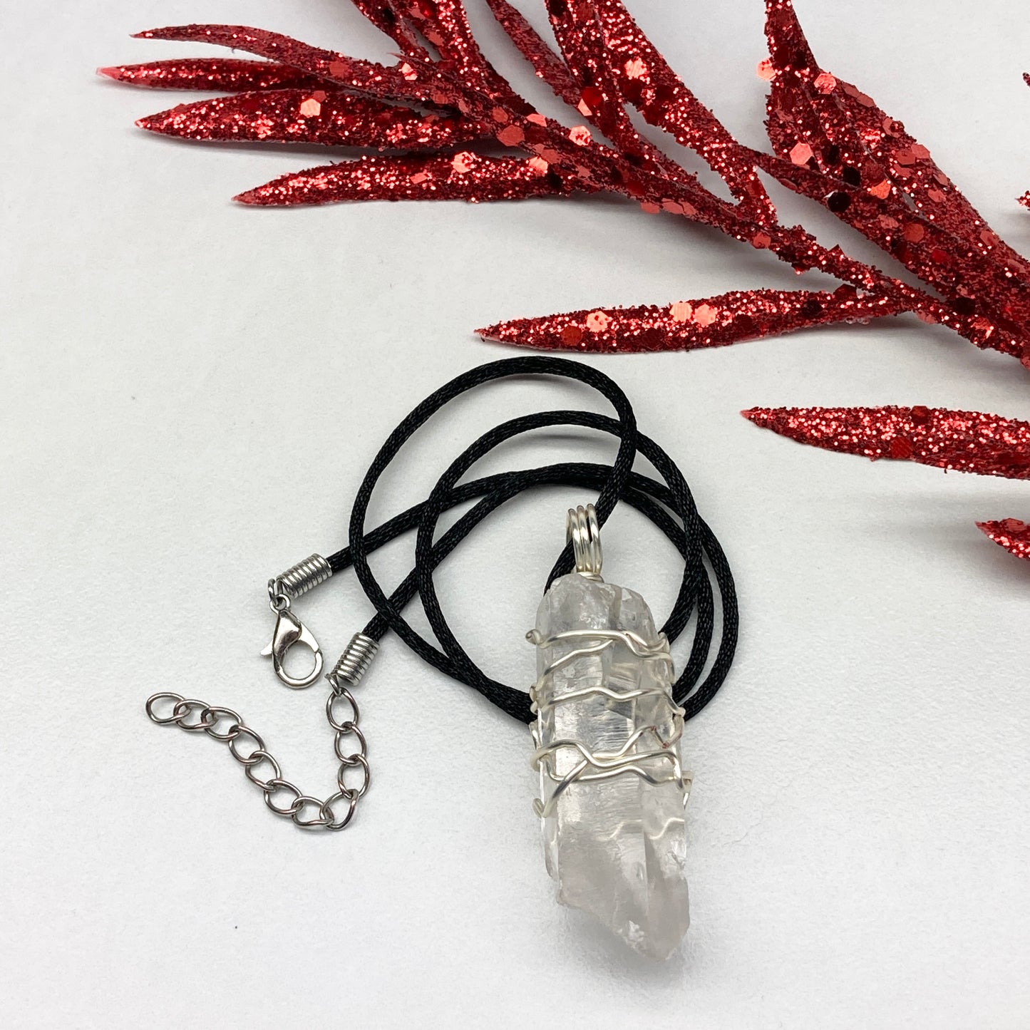 Clear Quartz necklace. Large Clear Quartz crystal wrapped with silver colored copper wire. Hangs on a black chain.