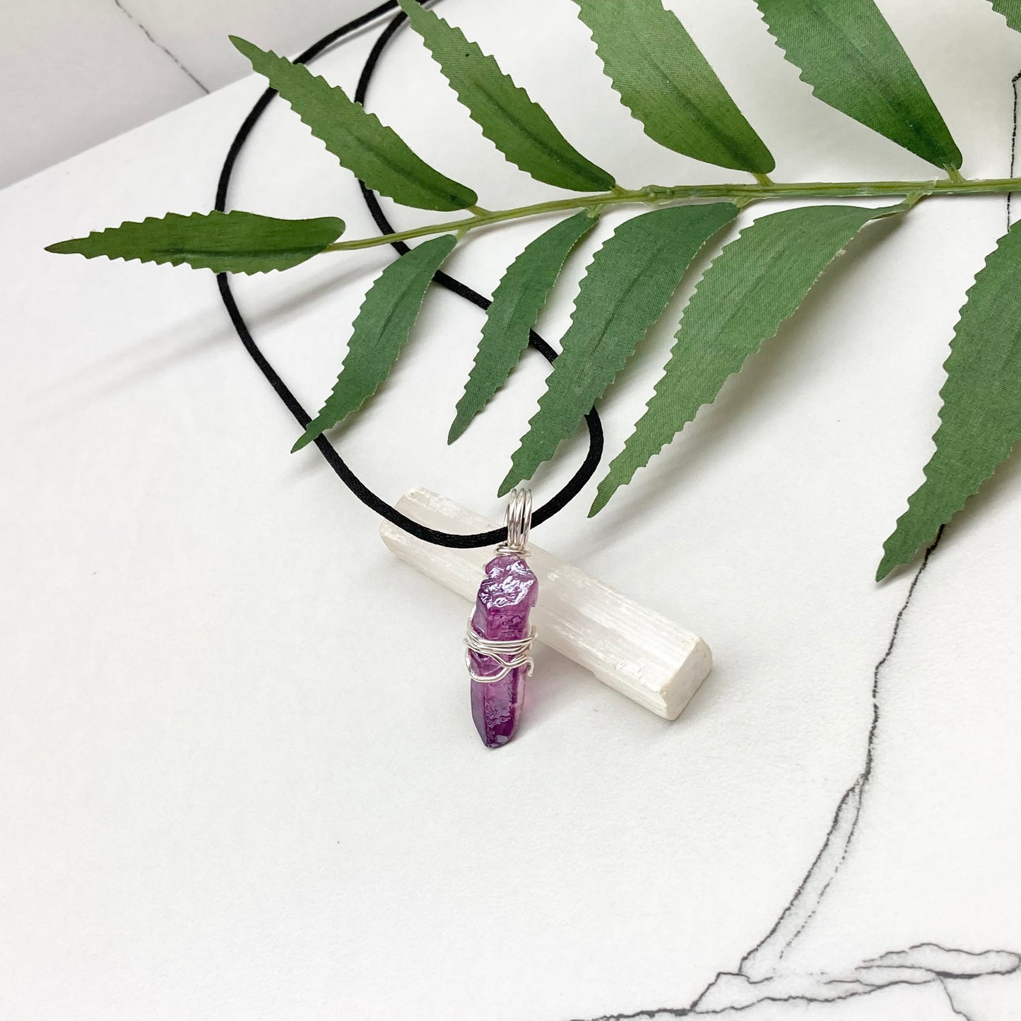 Hand-wrapped purple aura quartz pendant in silver-colored copper wire on a satin silk chain.