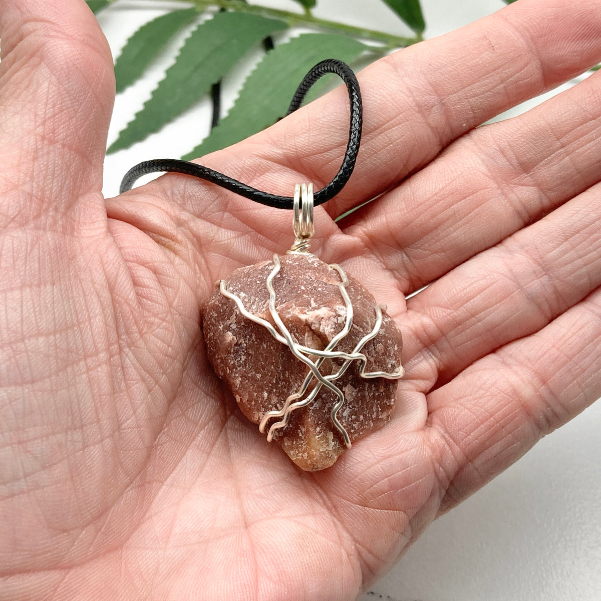 Red Aventurine necklace. Reddish brown stone wrapped with silver copper wire. Hangs on a black chain. Handcrafted spiritual jewelry.