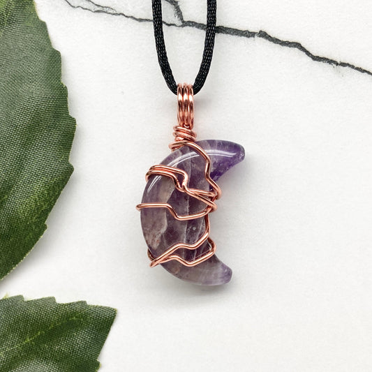 Amethyst Moon necklace. Crescent Moon shaped Amethyst crystal wrapped with copper wire. Hangs on a black chain. Moon lover jewelry.