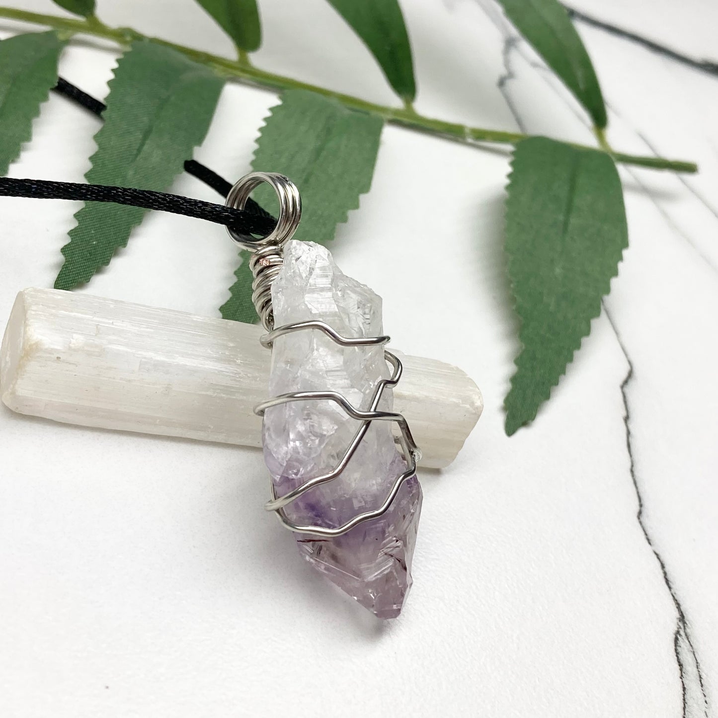 Amethyst tip necklace. Beautiful unique crystal that is Clear Quartz for the top half and purple amethyst for the bottom half. Crystal is wrapped with silver copper wire. Hangs on a black chain.