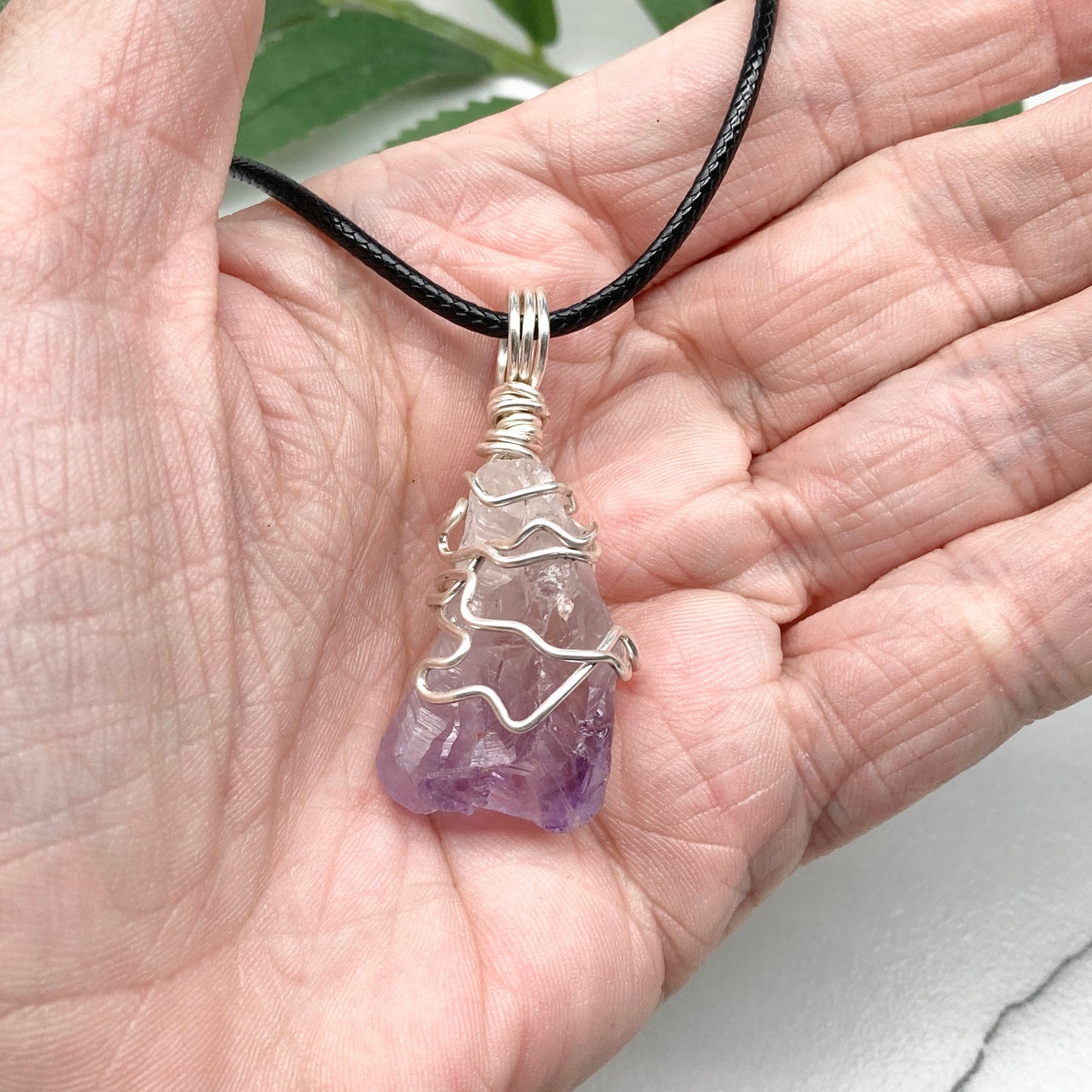 Amethyst tip necklace. Beautiful unique crystal that is Clear Quartz for the top half and purple amethyst for the bottom half. Crystal is wrapped with silver copper wire. Hangs on a black chain.
