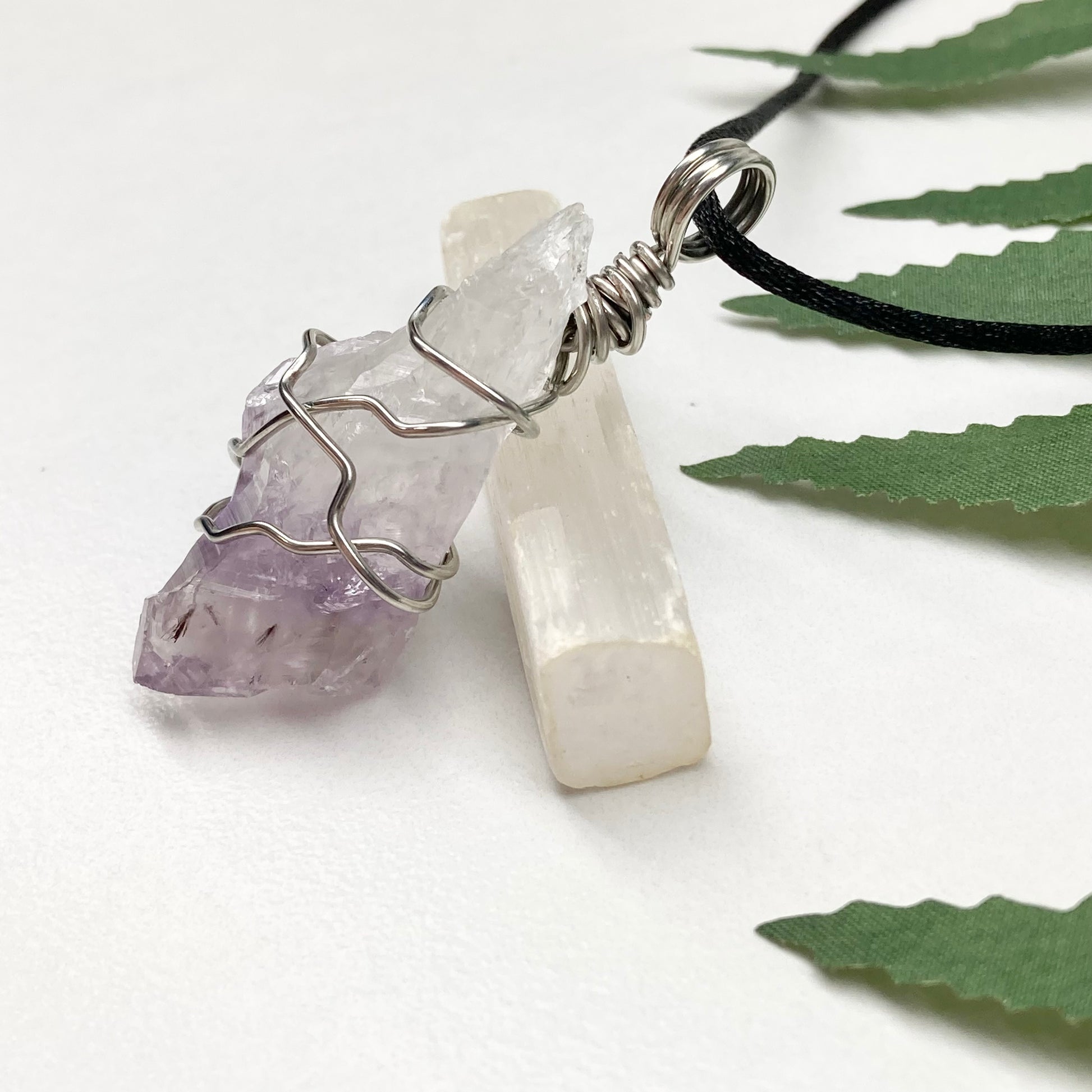 Amethyst tip necklace. Beautiful unique crystal that is Clear Quartz for the top half and purple amethyst for the bottom half. Crystal is wrapped with silver copper wire. Hangs on a black chain.
