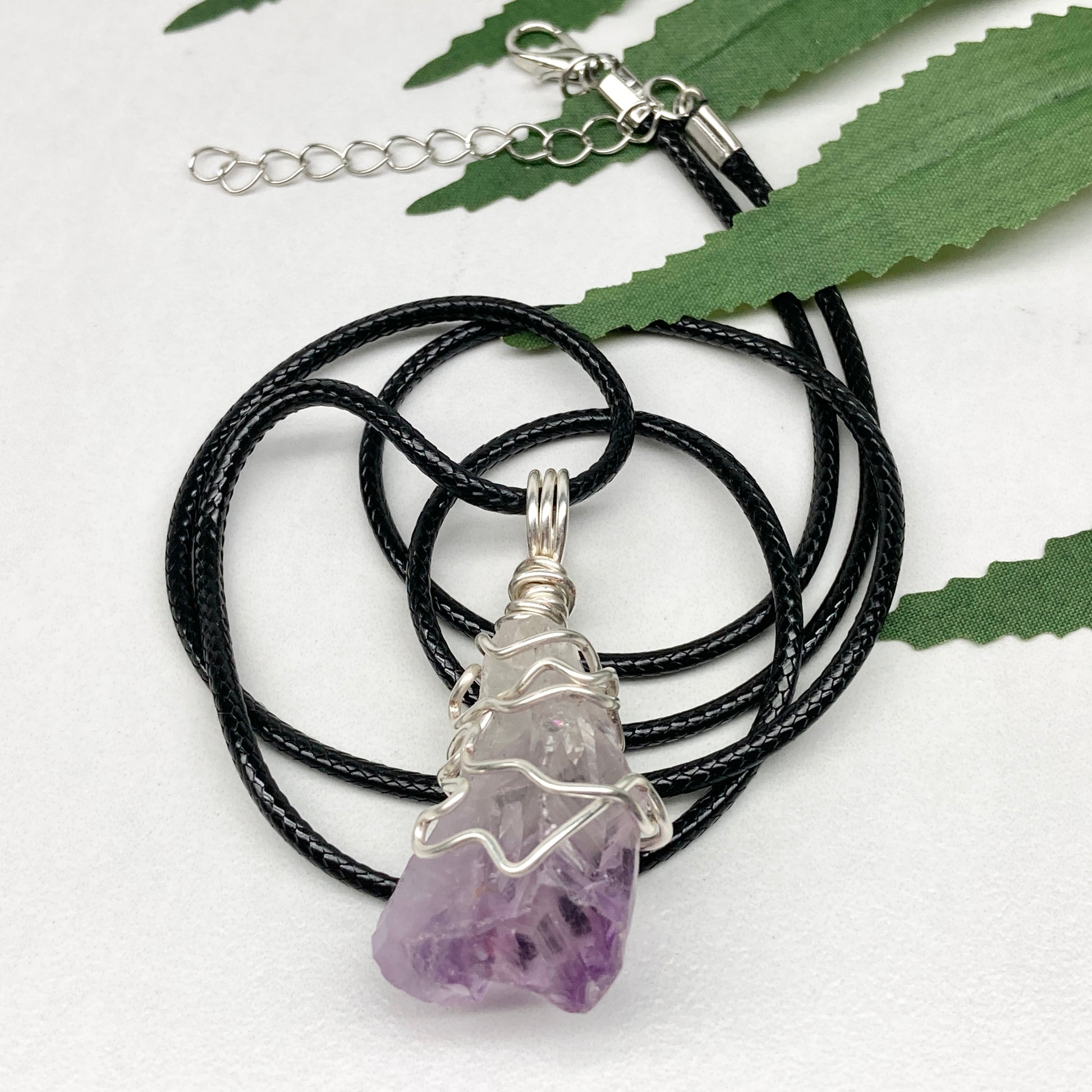 Amethyst tip necklace. Beautiful unique crystal that is Clear Quartz for the top half and purple amethyst for the bottom half. Crystal is wrapped with silver copper wire. Hangs on a black chain.