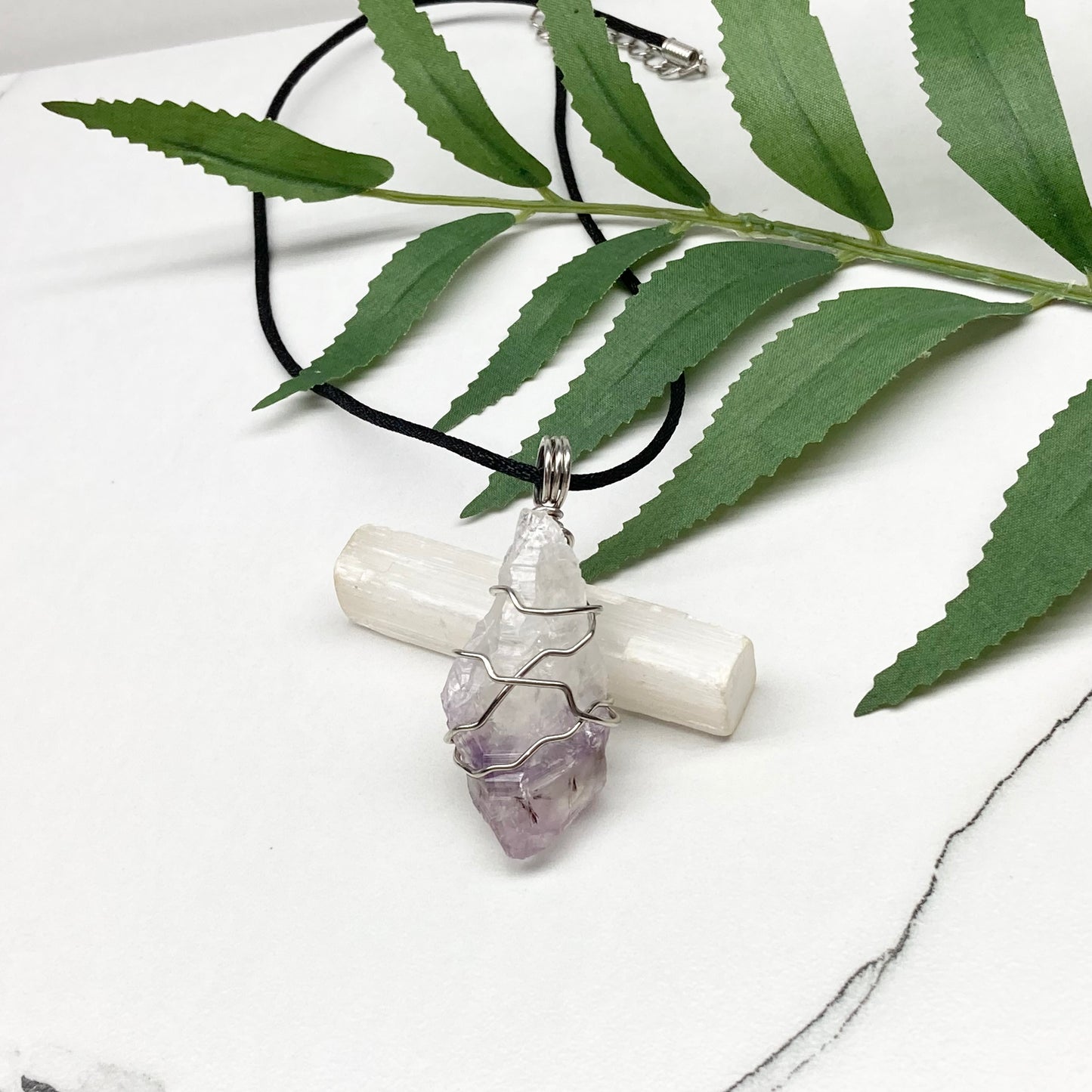 Amethyst tip necklace. Beautiful unique crystal that is Clear Quartz for the top half and purple amethyst for the bottom half. Crystal is wrapped with silver copper wire. Hangs on a black chain.