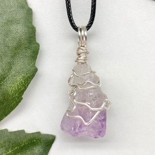 Amethyst tip necklace. Beautiful unique crystal that is Clear Quartz for the top half and purple amethyst for the bottom half. Crystal is wrapped with silver copper wire. Hangs on a black chain.