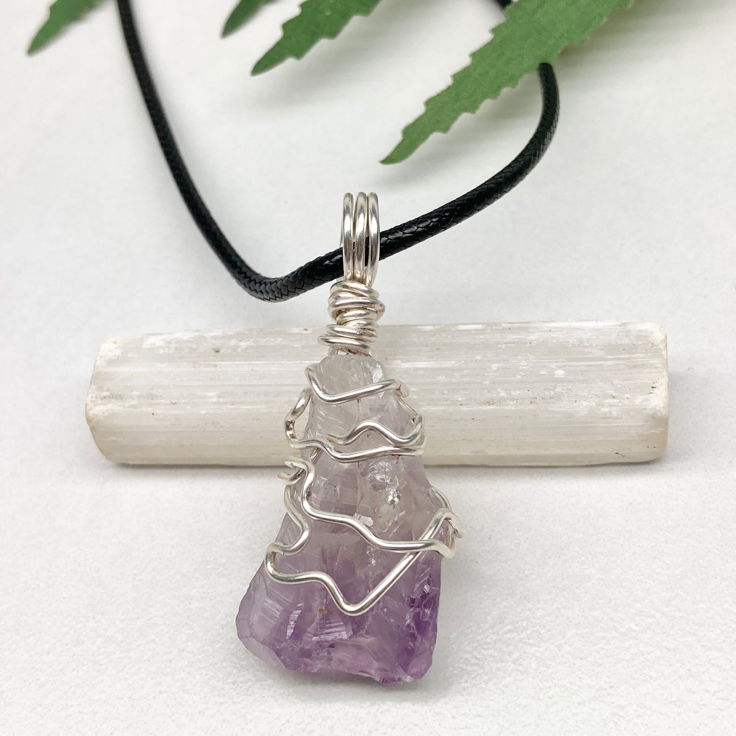 Amethyst tip necklace. Beautiful unique crystal that is Clear Quartz for the top half and purple amethyst for the bottom half. Crystal is wrapped with silver copper wire. Hangs on a black chain.