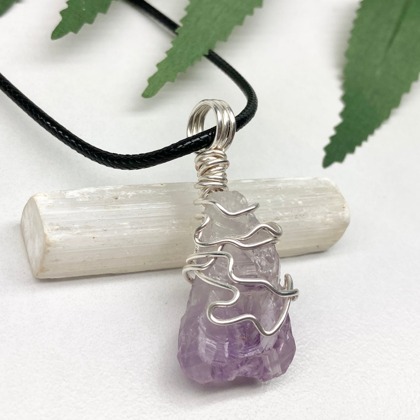 Amethyst tip necklace. Beautiful unique crystal that is Clear Quartz for the top half and purple amethyst for the bottom half. Crystal is wrapped with silver copper wire. Hangs on a black chain.