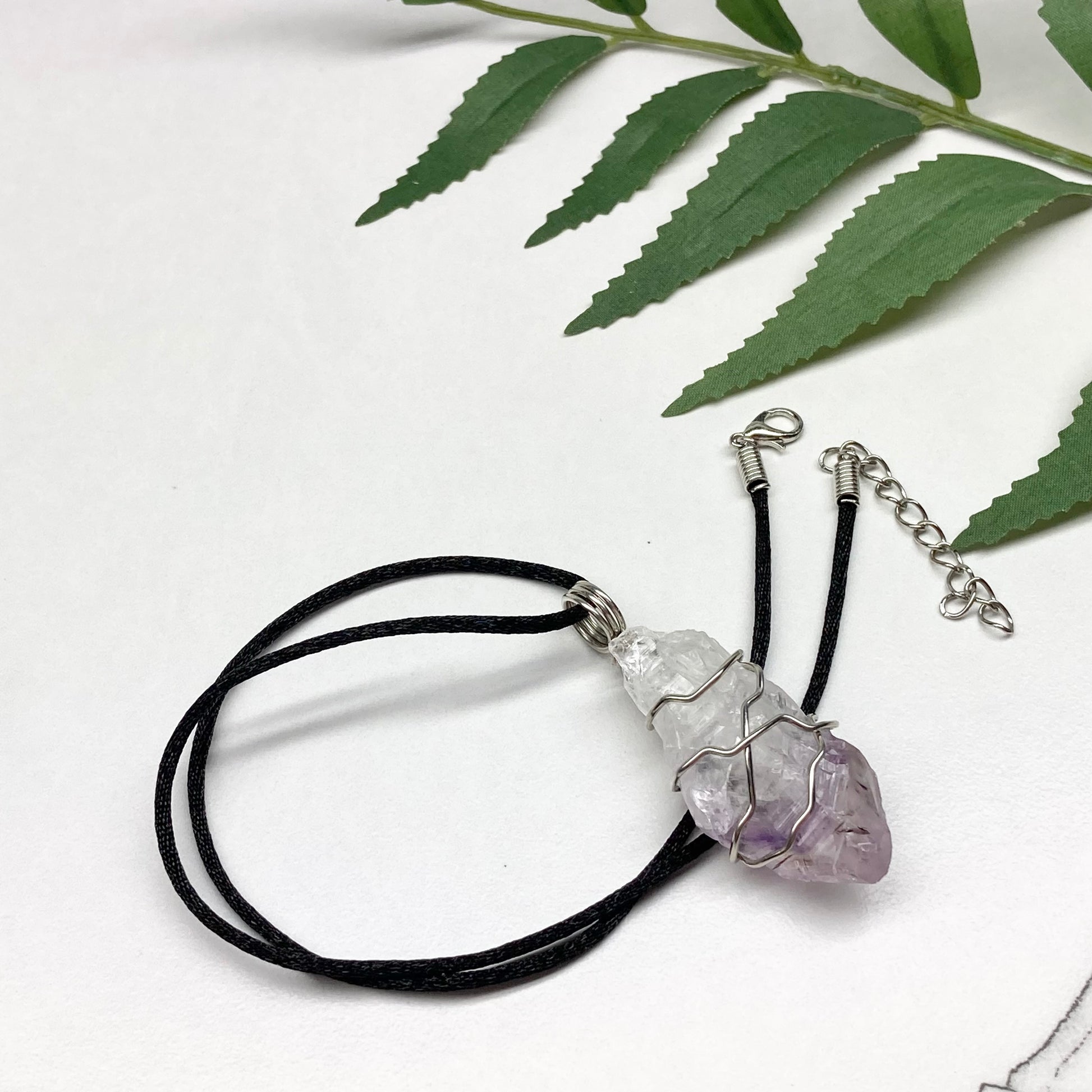Amethyst tip necklace. Beautiful unique crystal that is Clear Quartz for the top half and purple amethyst for the bottom half. Crystal is wrapped with silver copper wire. Hangs on a black chain.