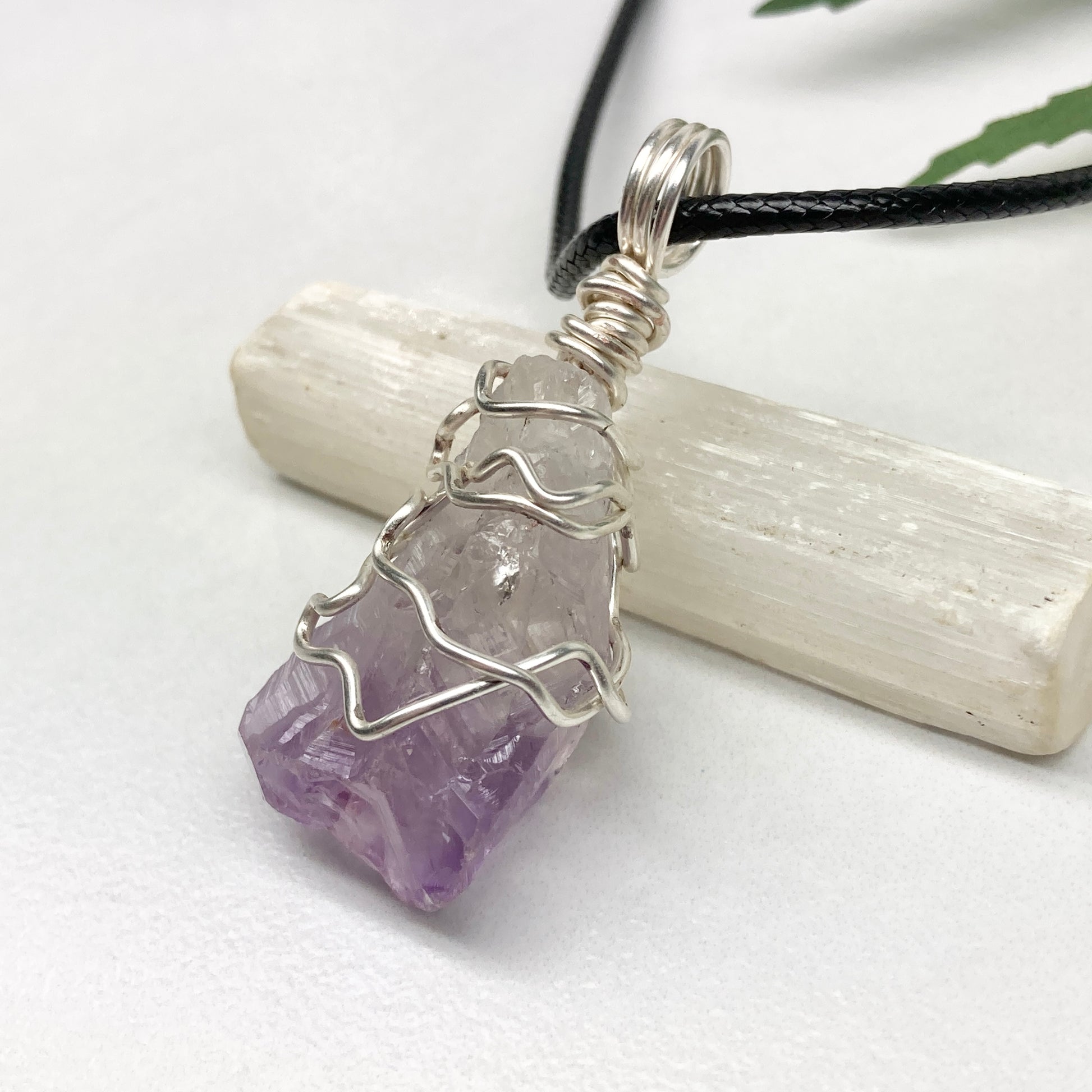 Amethyst tip necklace. Beautiful unique crystal that is Clear Quartz for the top half and purple amethyst for the bottom half. Crystal is wrapped with silver copper wire. Hangs on a black chain.