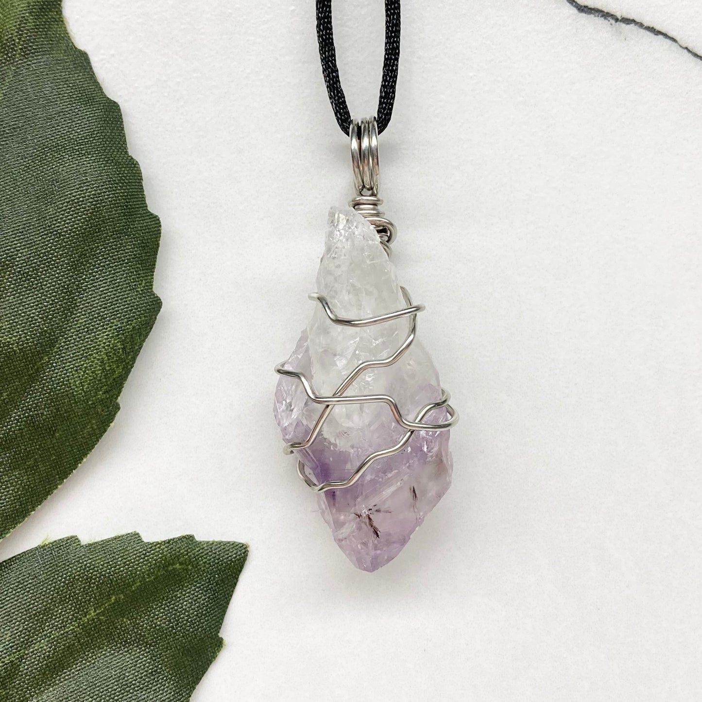 Amethyst tip necklace. Beautiful unique crystal that is Clear Quartz for the top half and purple amethyst for the bottom half. Crystal is wrapped with silver copper wire. Hangs on a black chain.