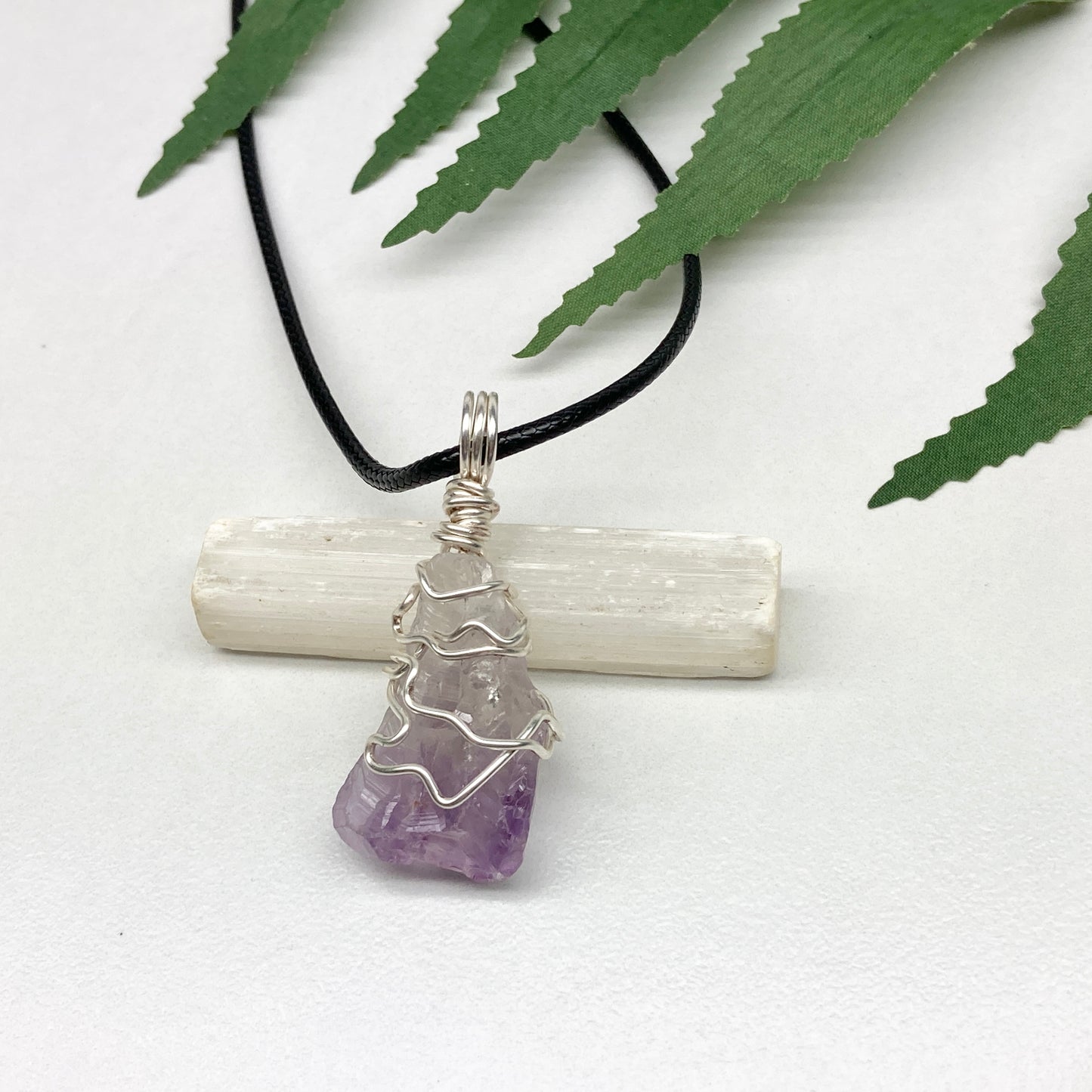 Amethyst tip necklace. Beautiful unique crystal that is Clear Quartz for the top half and purple amethyst for the bottom half. Crystal is wrapped with silver copper wire. Hangs on a black chain.