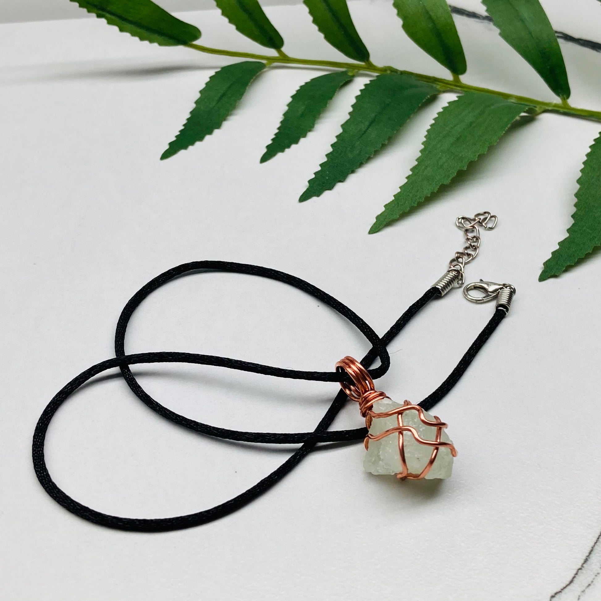 Aquamarine necklace. Raw light mint green stone wrapped with pure copper wire. Hangs on a black chain. Wire wrapped crystal jewelry.