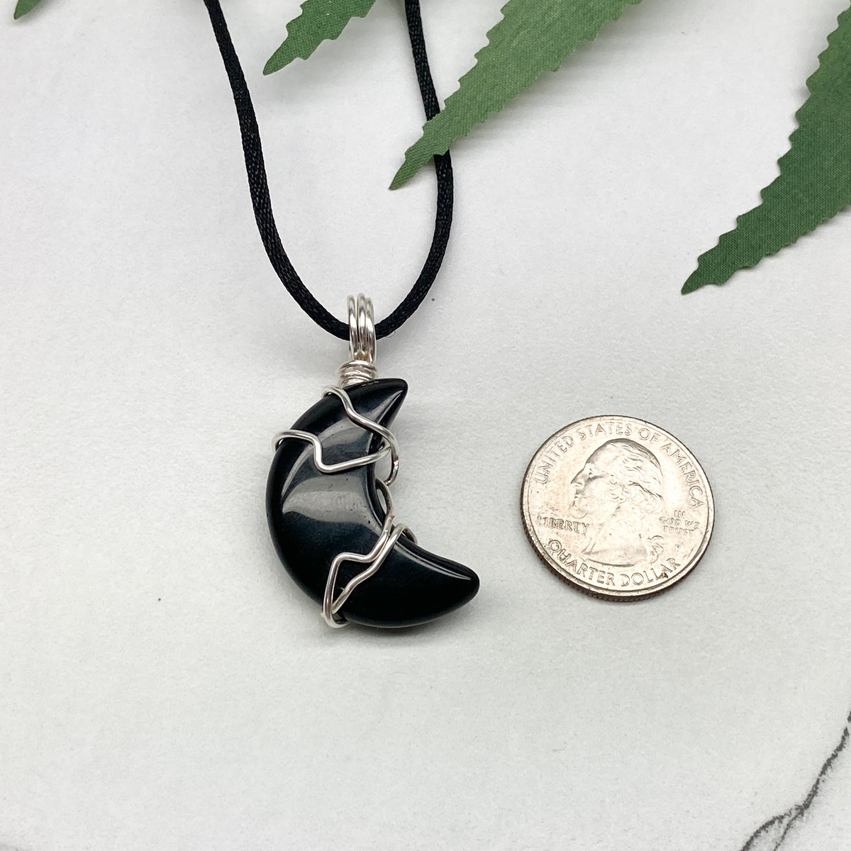 Black Onyx crescent moon necklace wrapped in silver-colored copper wire on a black necklace. One-of-a-kind pendant handmade during the Moon in Pisces.