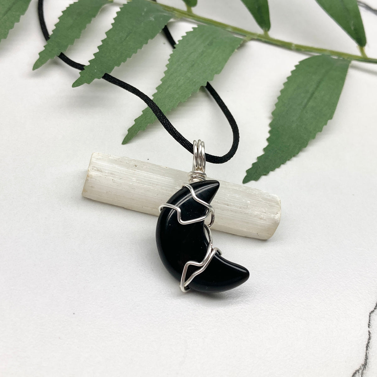 Black Onyx crescent moon necklace wrapped in silver-colored copper wire on a black necklace. One-of-a-kind pendant handmade during the Moon in Pisces.