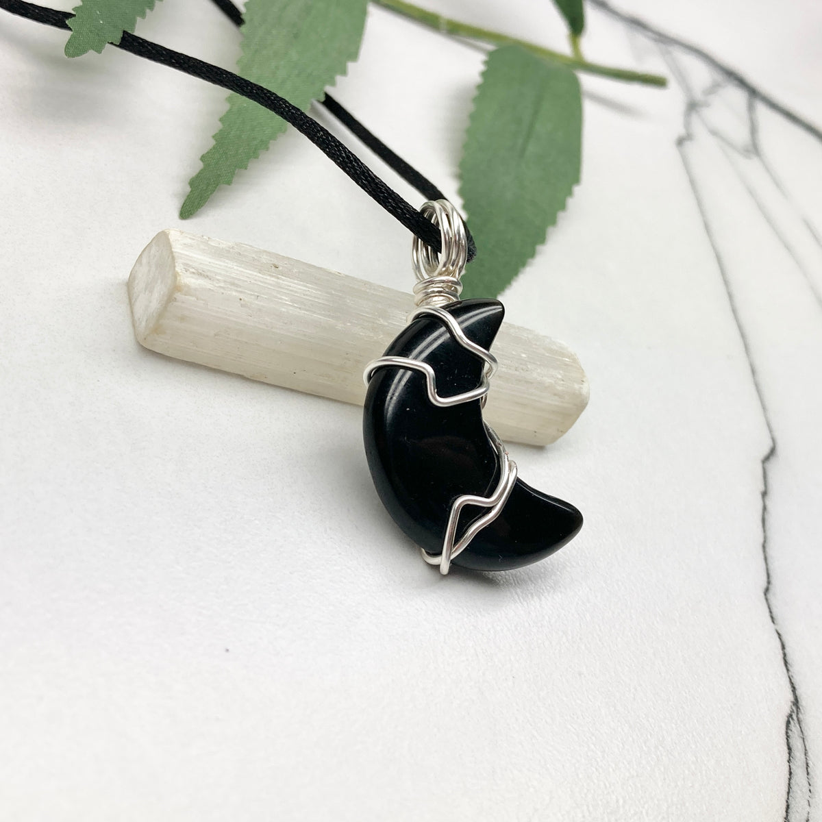 Black Onyx crescent moon necklace wrapped in silver-colored copper wire on a black necklace. One-of-a-kind pendant handmade during the Moon in Pisces.