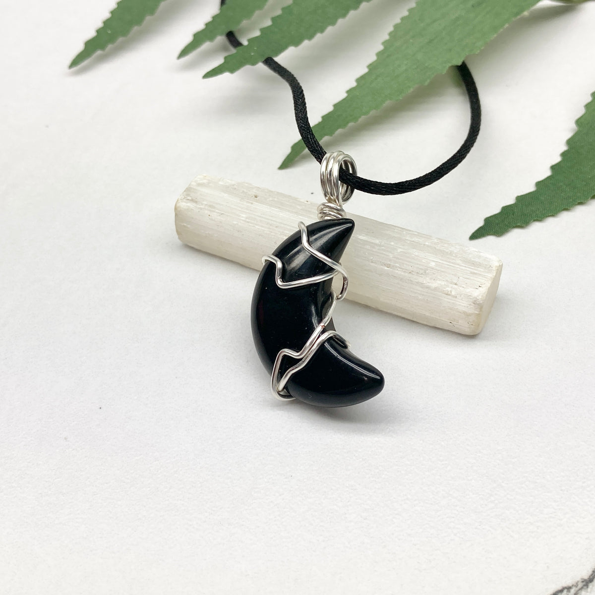 Black Onyx crescent moon necklace wrapped in silver-colored copper wire on a black necklace. One-of-a-kind pendant handmade during the Moon in Pisces.