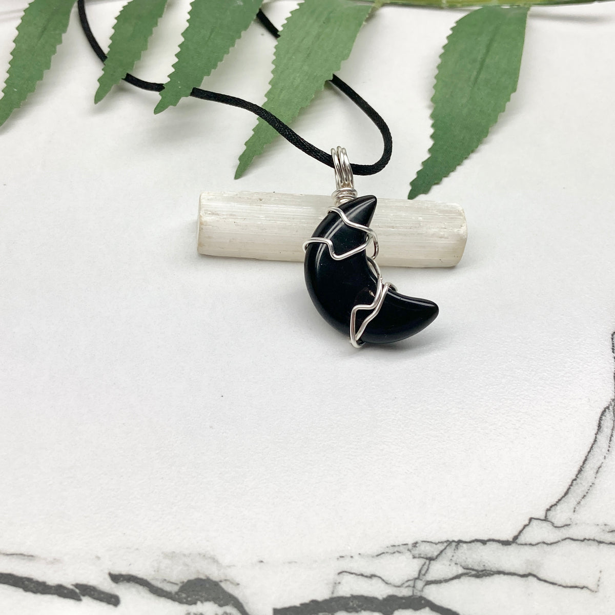 Black Onyx crescent moon necklace wrapped in silver-colored copper wire on a black necklace. One-of-a-kind pendant handmade during the Moon in Pisces.