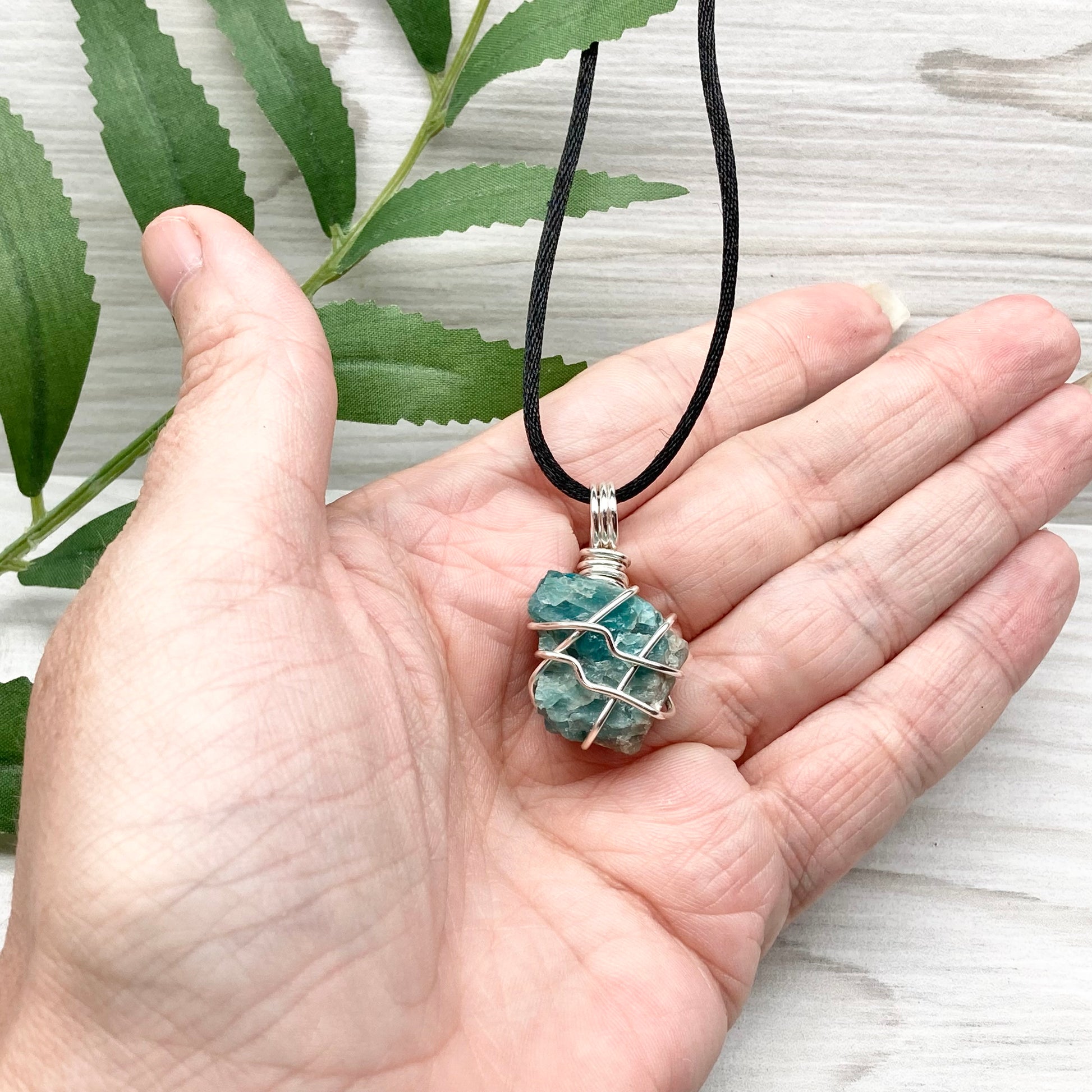 Blue Apatite necklace. Blue stone wrapped with silver copper wire. Hangs on a black chain.