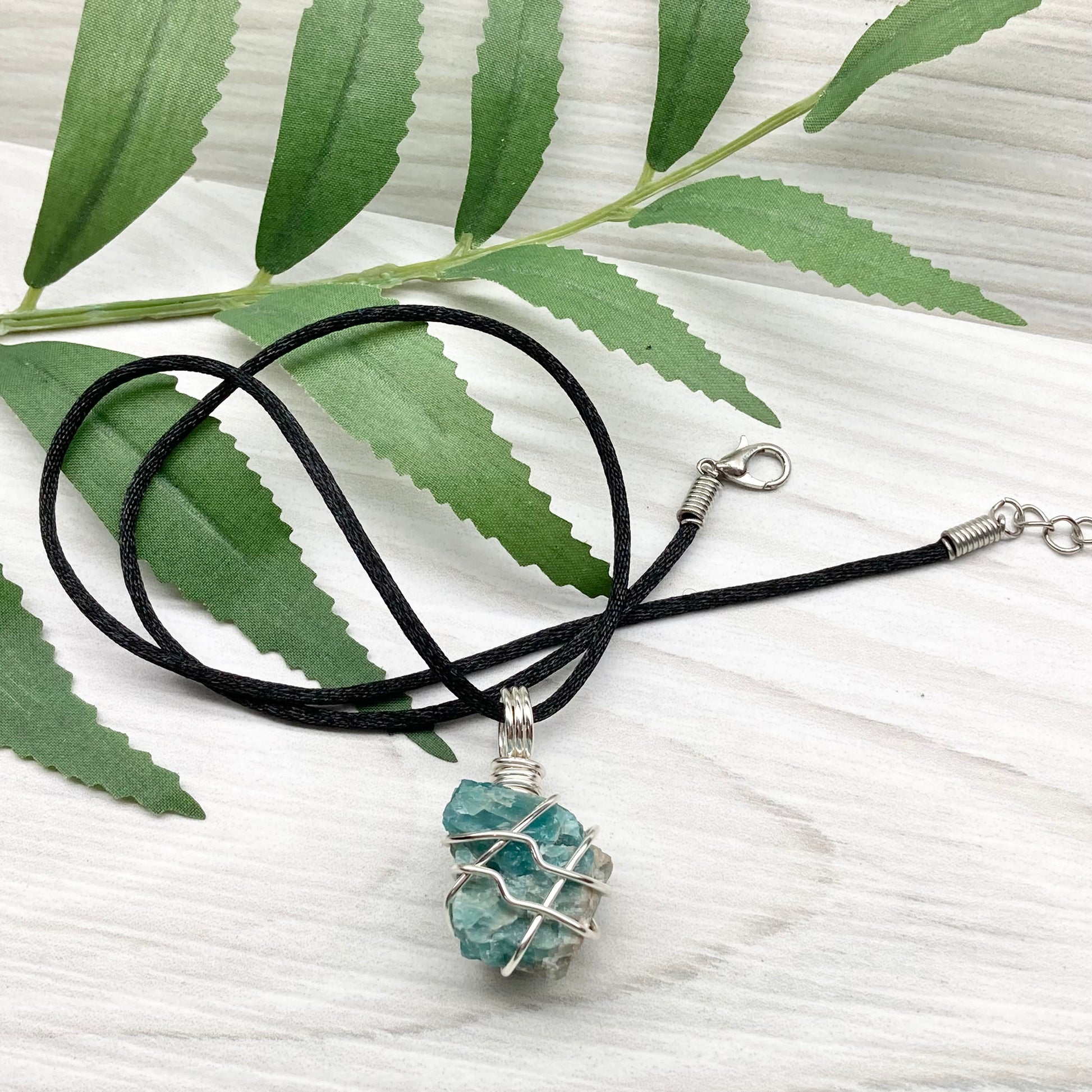 Blue Apatite necklace. Blue stone wrapped with silver copper wire. Hangs on a black chain.