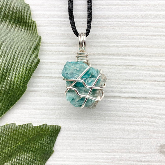 Blue Apatite necklace. Blue stone wrapped with silver copper wire. Hangs on a black chain.