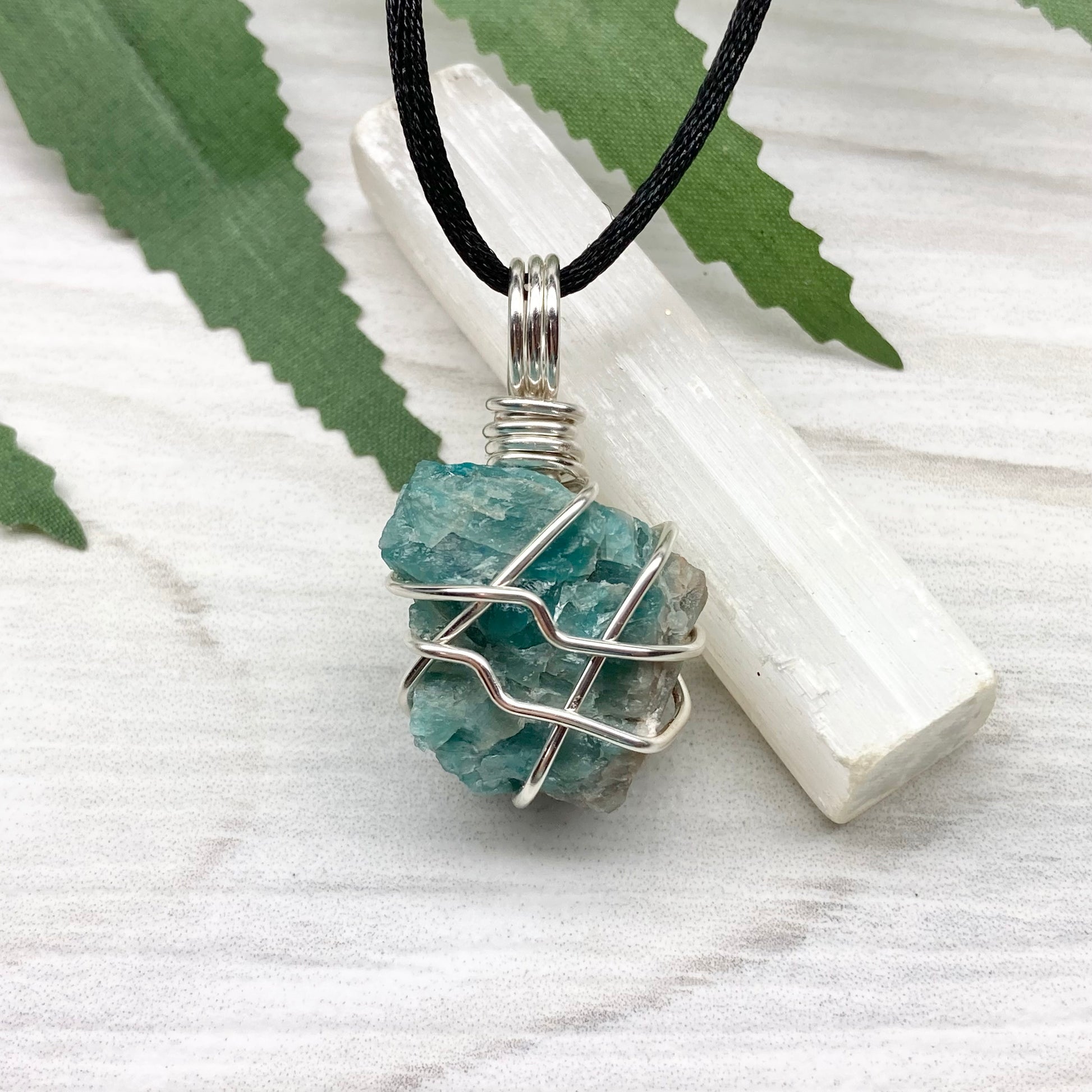 Blue Apatite necklace. Blue stone wrapped with silver copper wire. Hangs on a black chain.