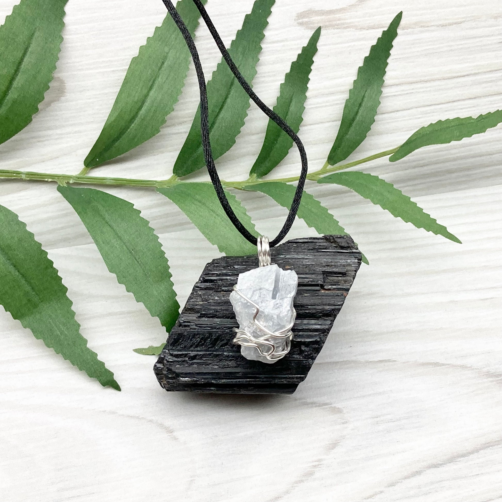 Natural Blue Calcite Necklace. Blue Calcite crystal wrapped with tarnish resistant silver colored copper wire. Pendant comes on a black lobster claw necklace with silver ends.