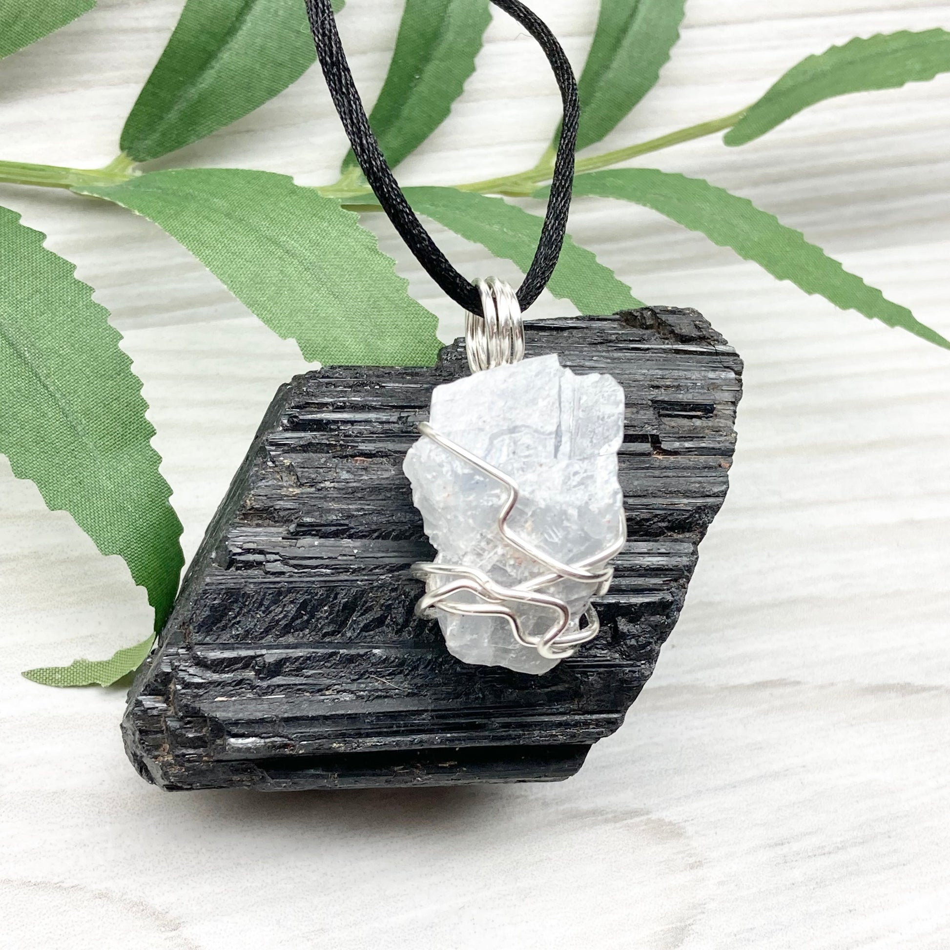 Natural Blue Calcite Necklace. Blue Calcite crystal wrapped with tarnish resistant silver colored copper wire. Pendant comes on a black lobster claw necklace with silver ends.