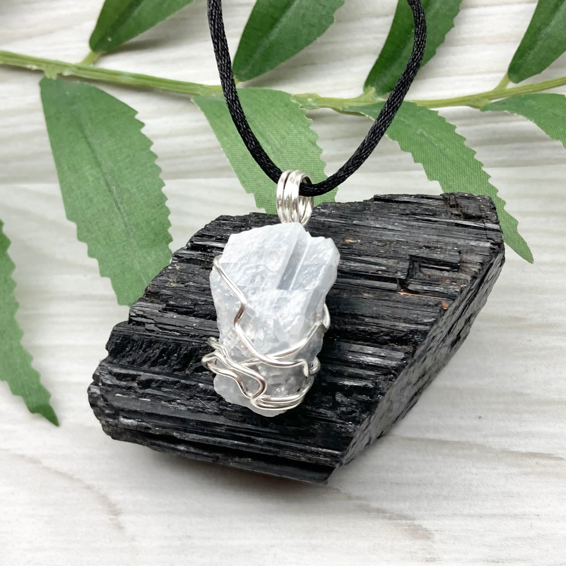 Natural Blue Calcite Necklace. Blue Calcite crystal wrapped with tarnish resistant silver colored copper wire. Pendant comes on a black lobster claw necklace with silver ends.