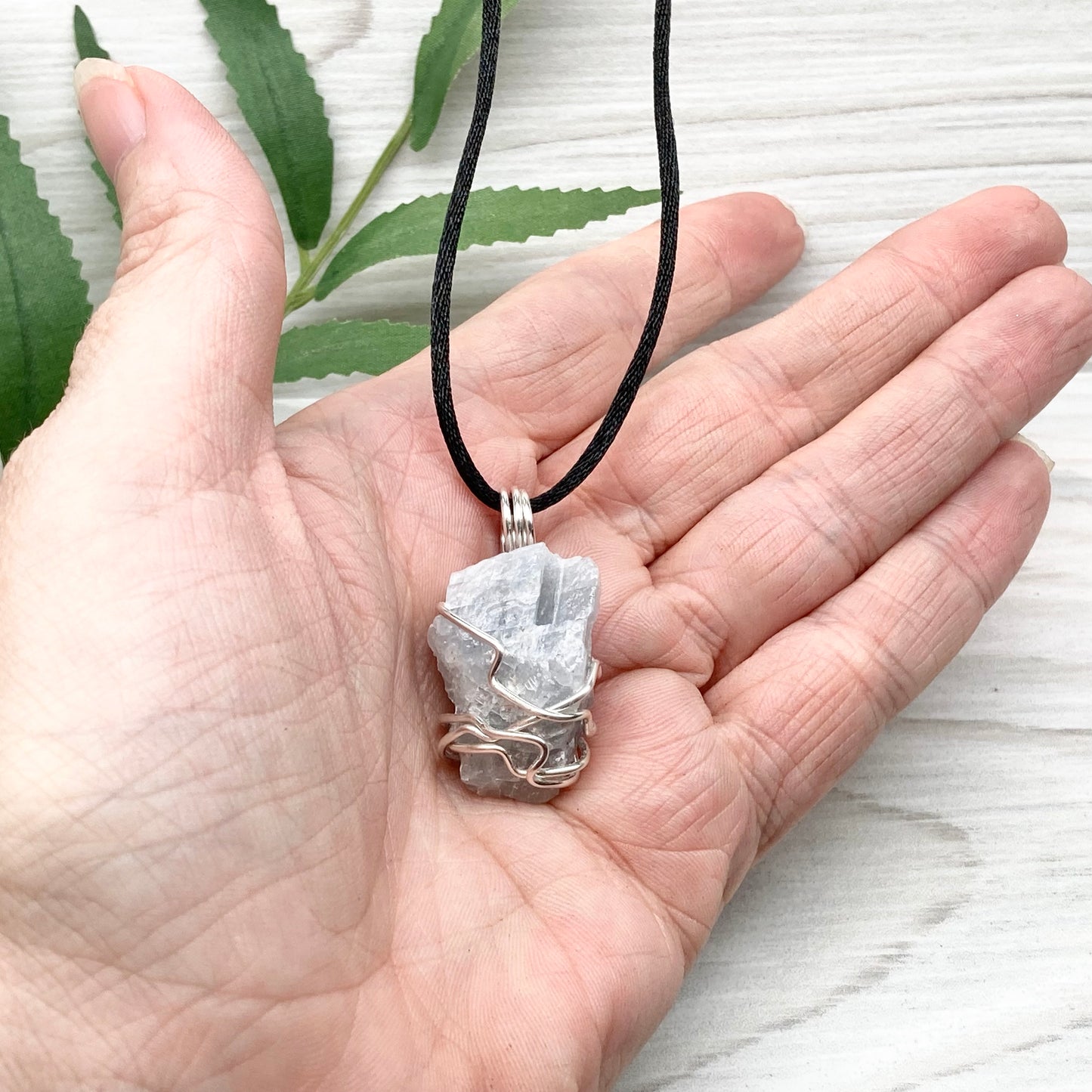 Natural Blue Calcite Necklace. Blue Calcite crystal wrapped with tarnish resistant silver colored copper wire. Pendant comes on a black lobster claw necklace with silver ends.