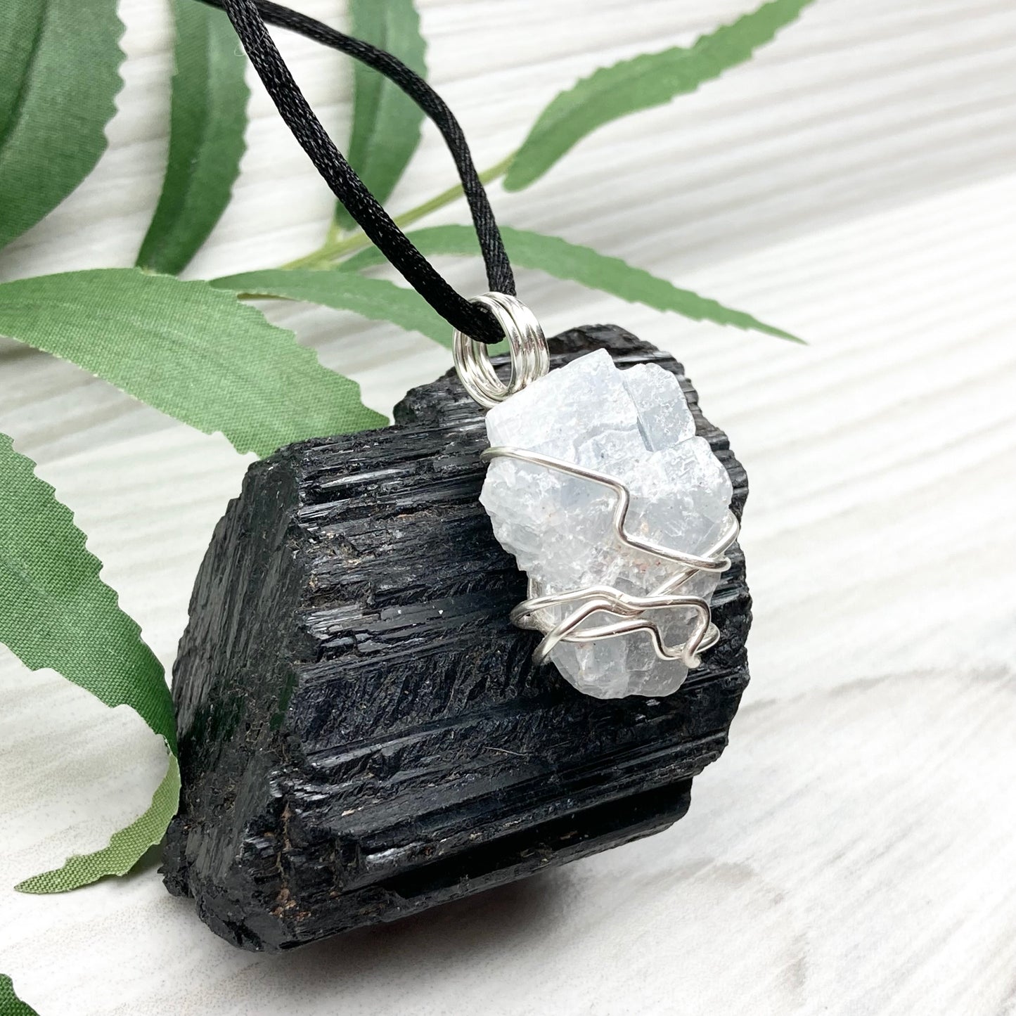 Natural Blue Calcite Necklace. Blue Calcite crystal wrapped with tarnish resistant silver colored copper wire. Pendant comes on a black lobster claw necklace with silver ends.