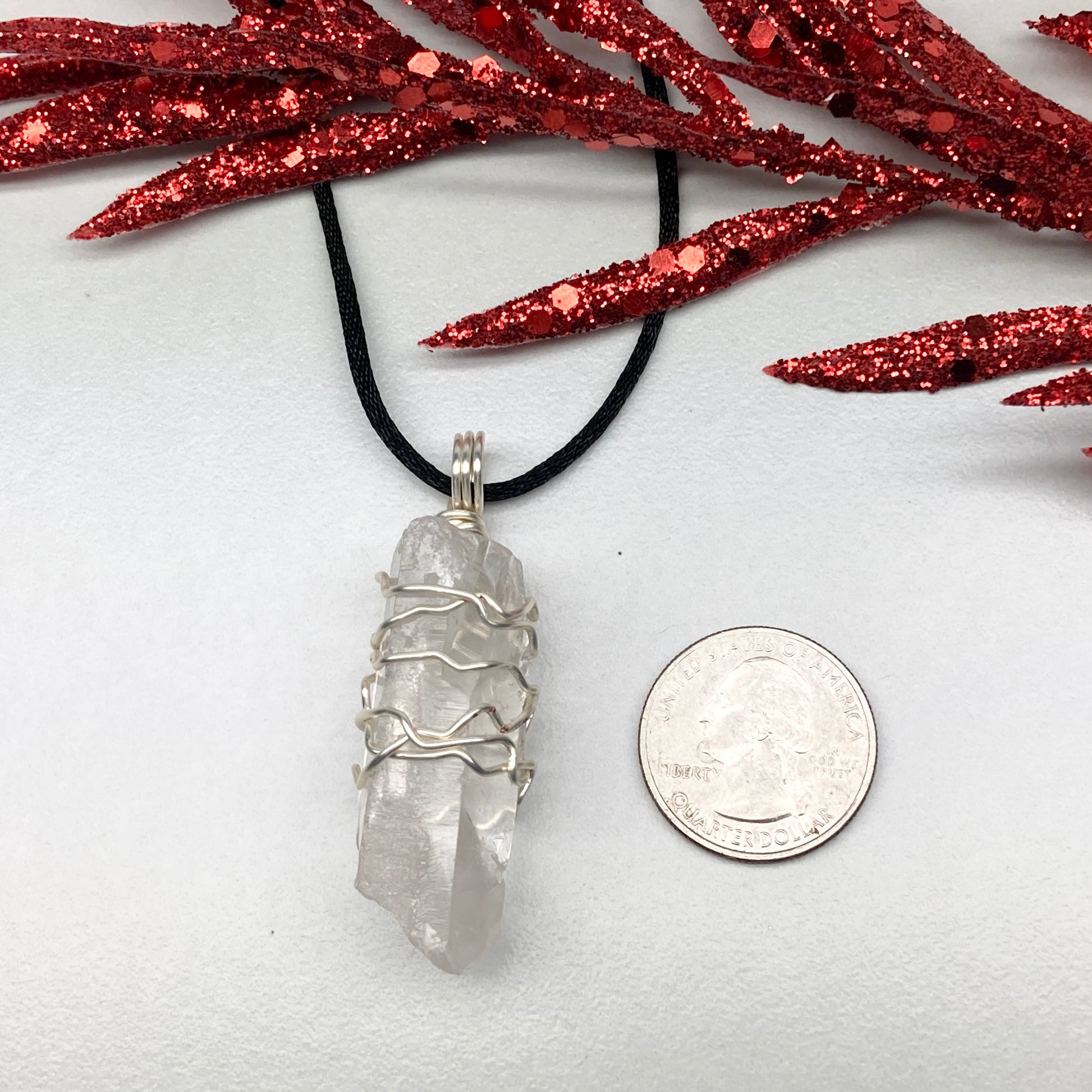 Clear Quartz necklace. Large Clear Quartz crystal wrapped with silver colored copper wire. Hangs on a black chain.
