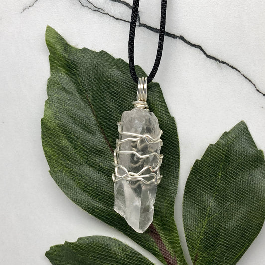 Clear Quartz necklace. Large Clear Quartz crystal wrapped with silver colored copper wire. Hangs on a black chain.