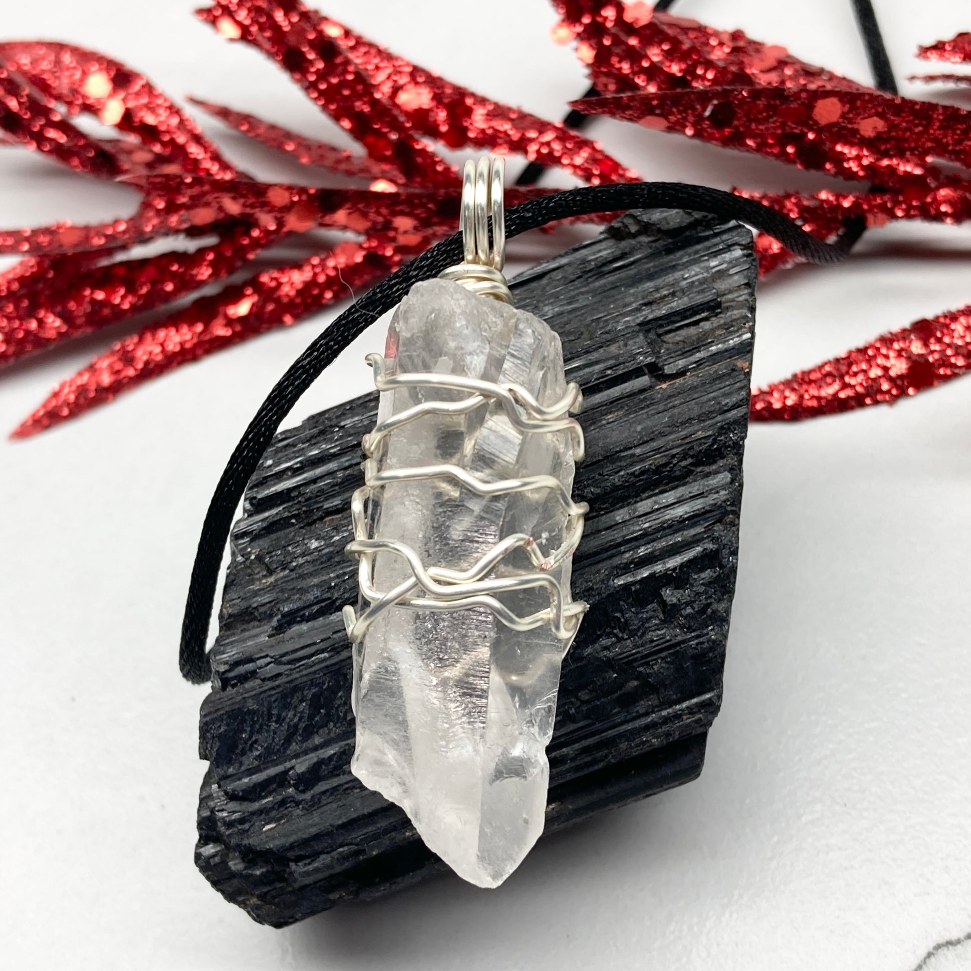Clear Quartz necklace. Large Clear Quartz crystal wrapped with silver colored copper wire. Hangs on a black chain.