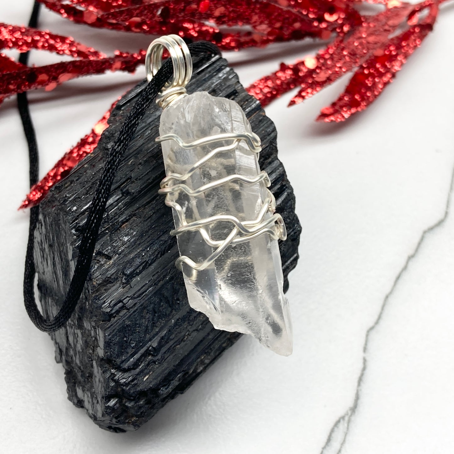 Clear Quartz necklace. Large Clear Quartz crystal wrapped with silver colored copper wire. Hangs on a black chain.
