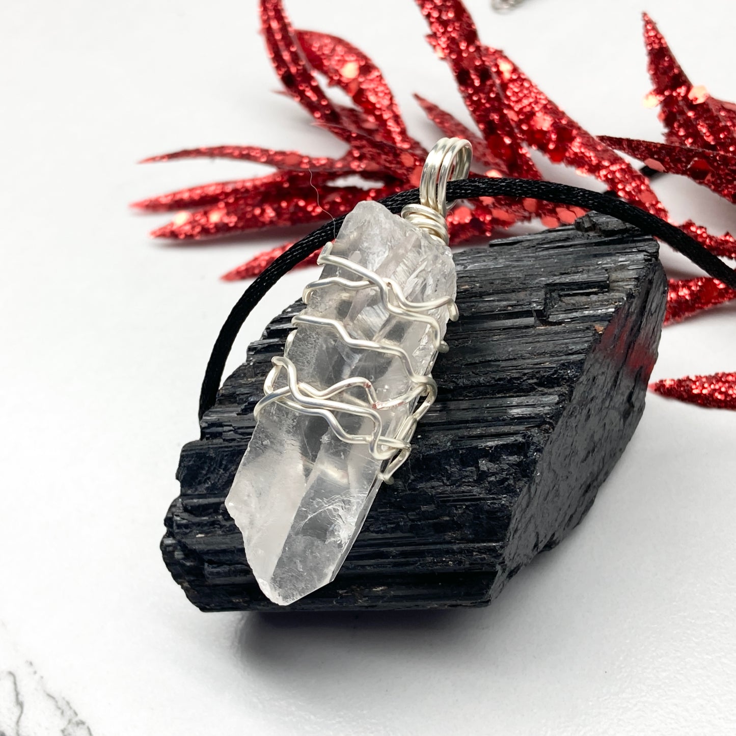 Clear Quartz necklace. Large Clear Quartz crystal wrapped with silver colored copper wire. Hangs on a black chain.