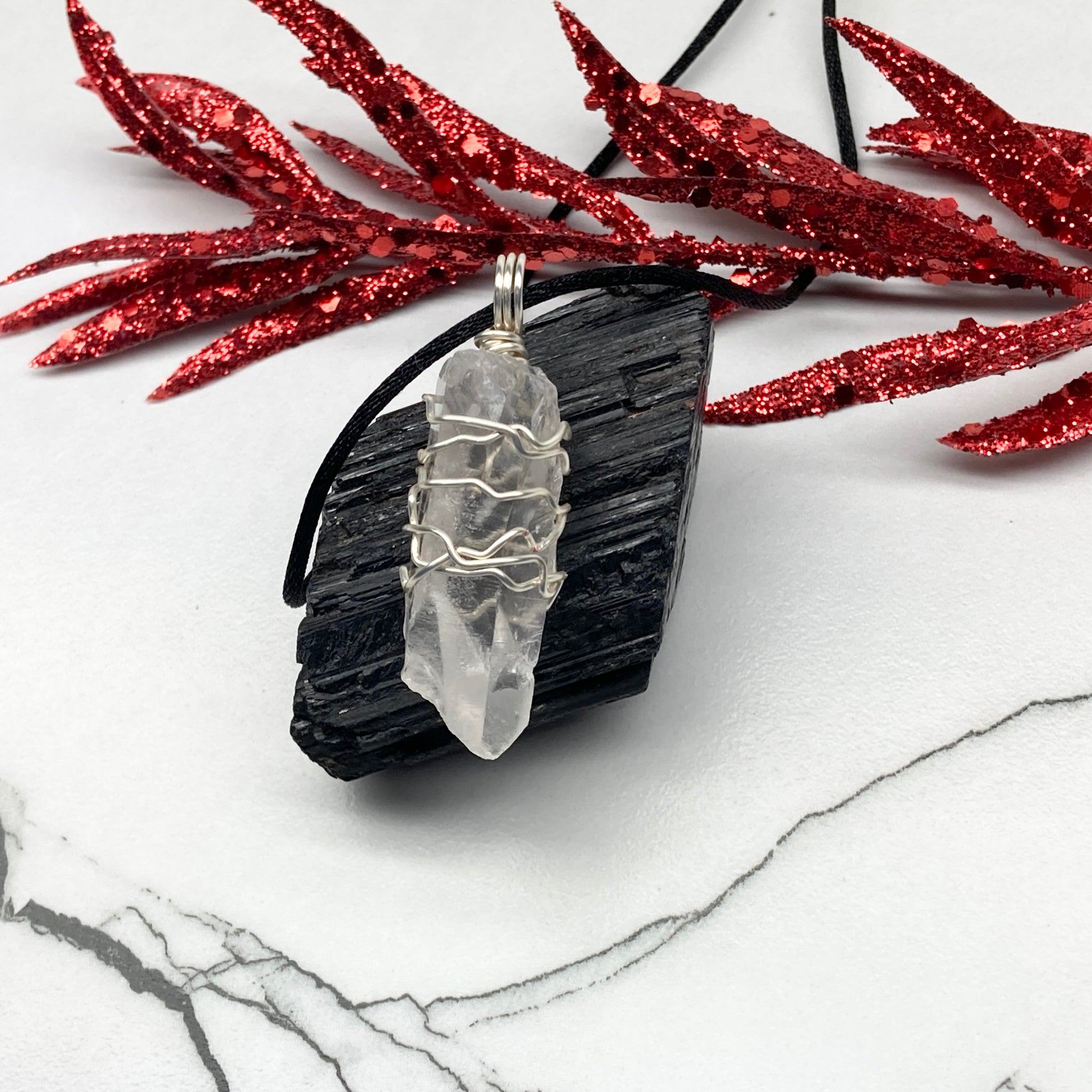 Clear Quartz necklace. Large Clear Quartz crystal wrapped with silver colored copper wire. Hangs on a black chain.