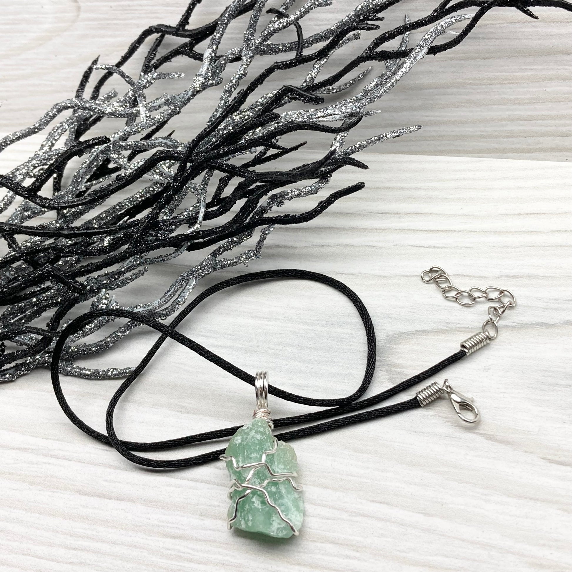 Green Aventurine necklace. Raw Green Aventurine stone wrapped with silver colored copper wire. Comes on a black chain. Wire wrapped green crystal pendant. 