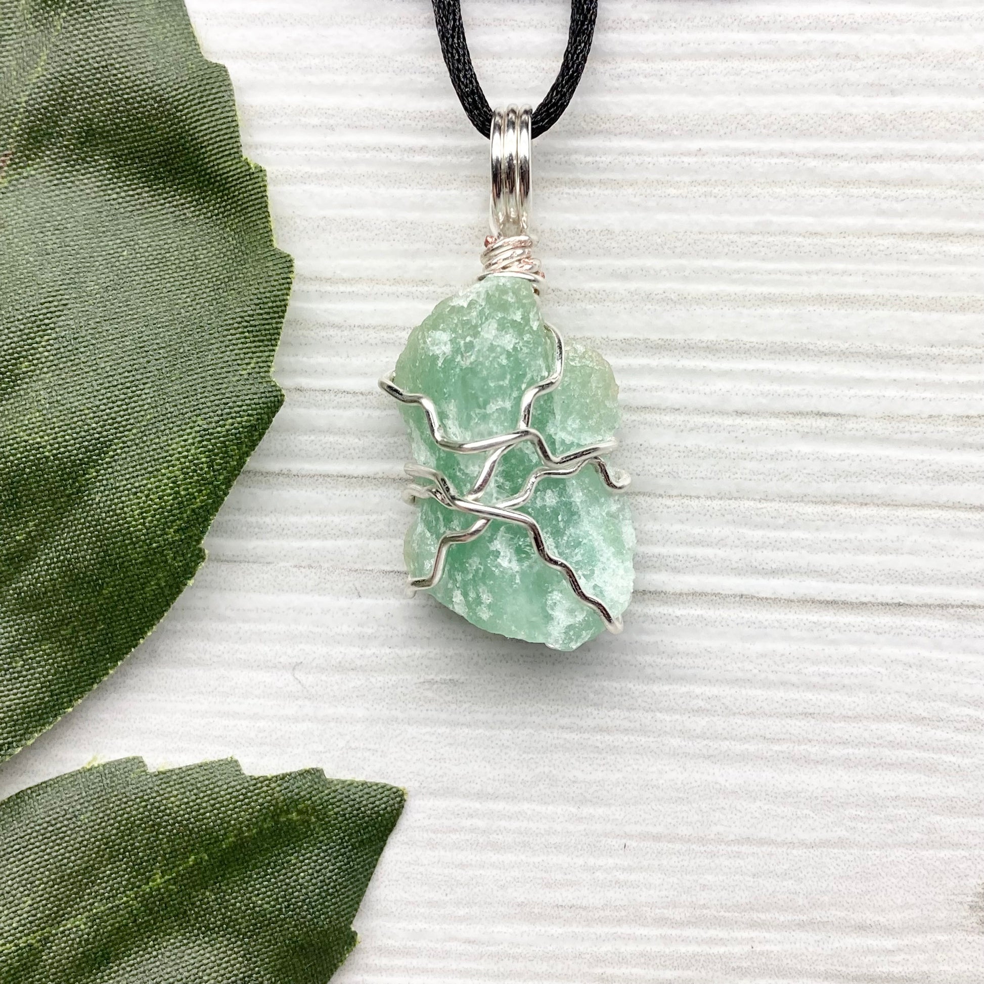 Green Aventurine necklace. Raw Green Aventurine stone wrapped with silver colored copper wire. Comes on a black chain. Wire wrapped green crystal pendant. 