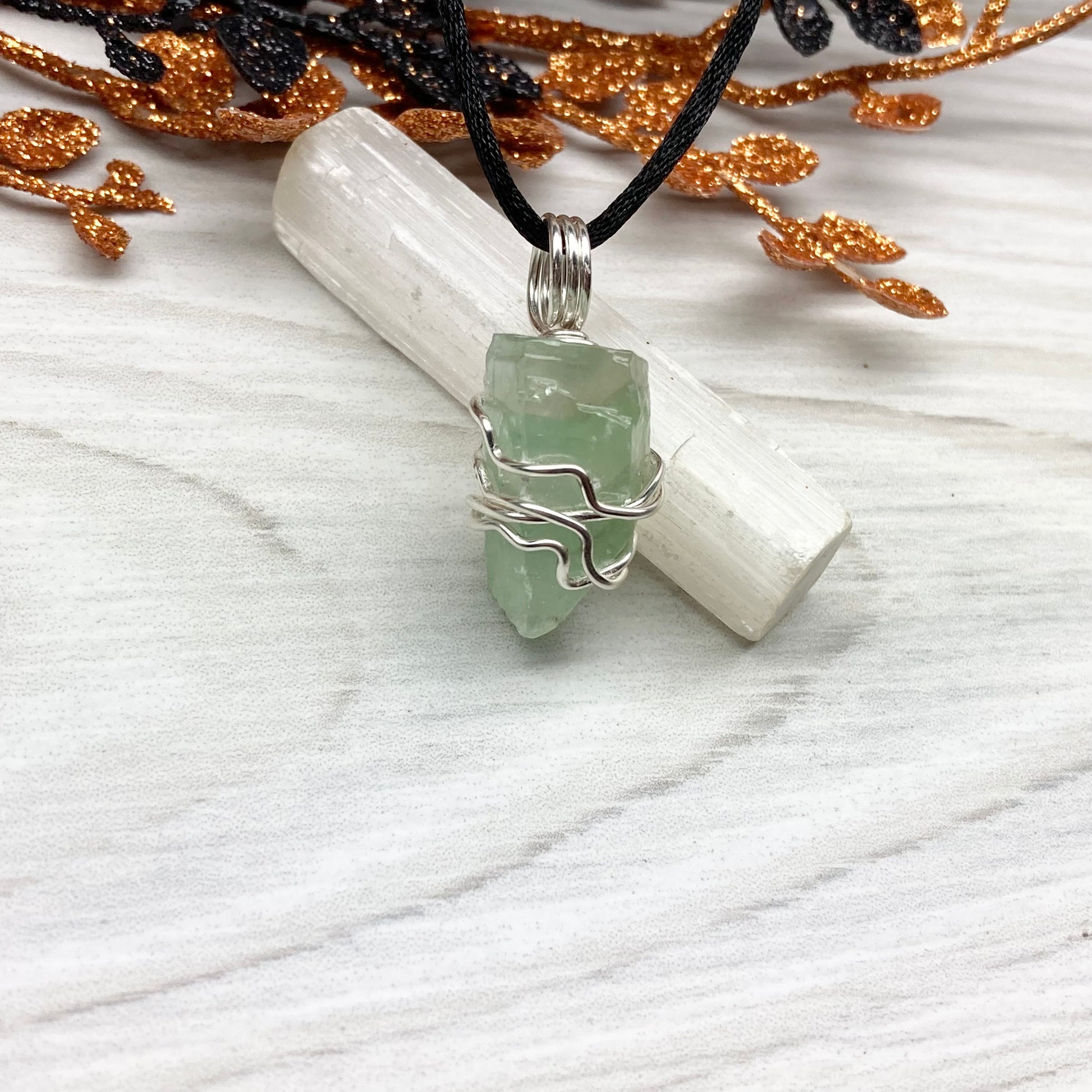 Green Calcite Necklace. Green Calcite wrapped with silver colored copper wire. Comes on a black chain. Wire wrapped green crystal pendant. 