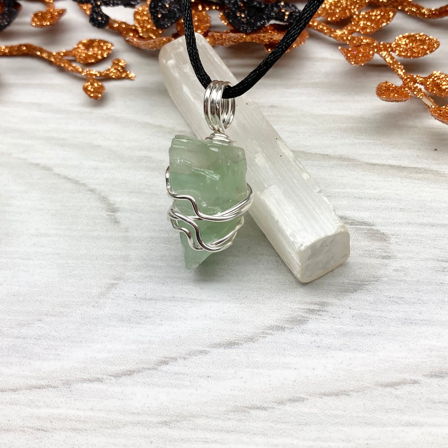 Green Calcite Necklace. Green Calcite wrapped with silver colored copper wire. Comes on a black chain. Wire wrapped green crystal pendant. 