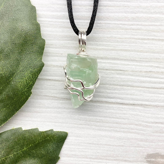 Green Calcite Necklace. Green Calcite wrapped with silver colored copper wire. Comes on a black chain. Wire wrapped green crystal pendant. 