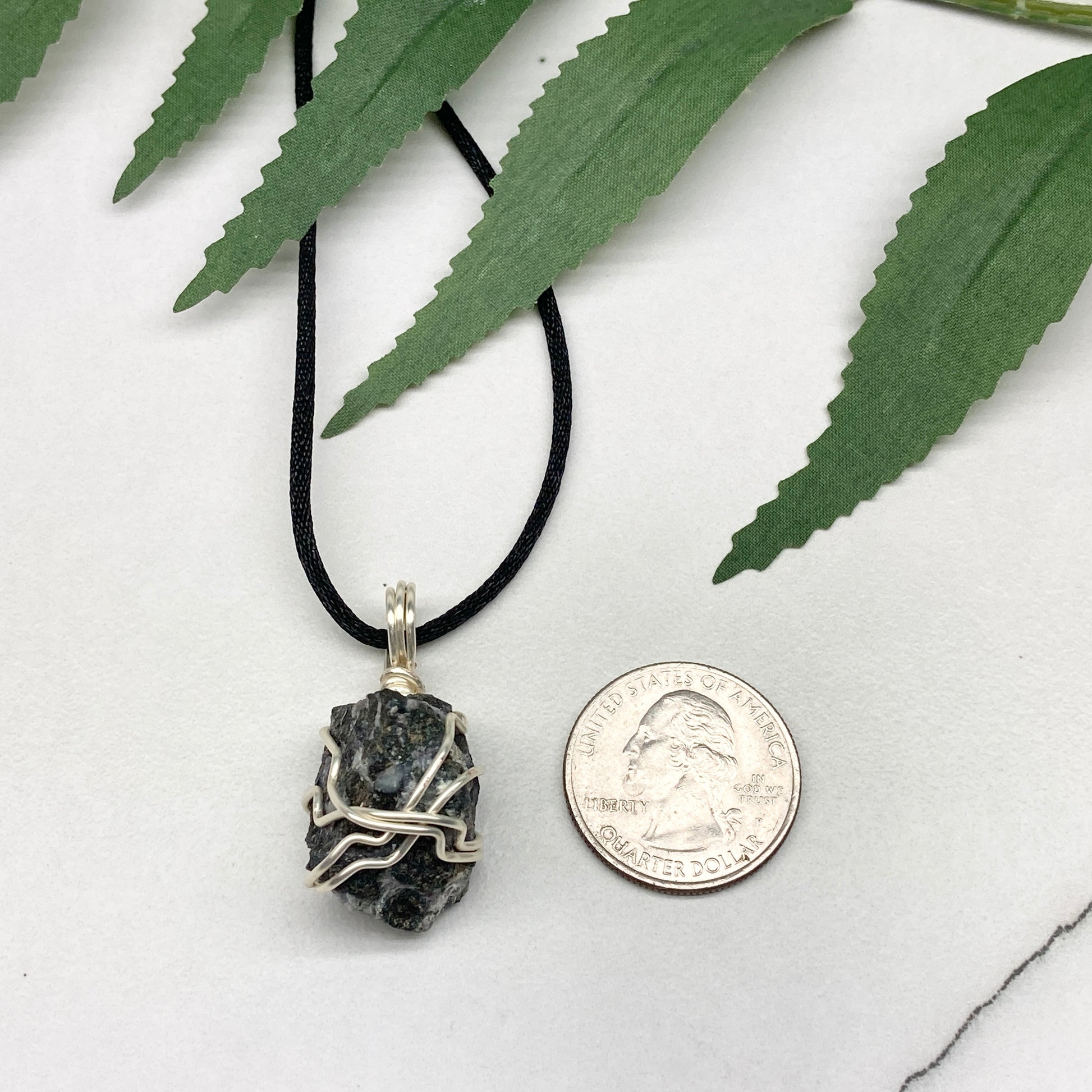 Indigo Gabbro necklace. Raw Indigo Gabbro stone wrapped with tarnish resistant wire. Hangs on a black chain. Also known as Mystic Merlinite. Gray and black marbled crystal.