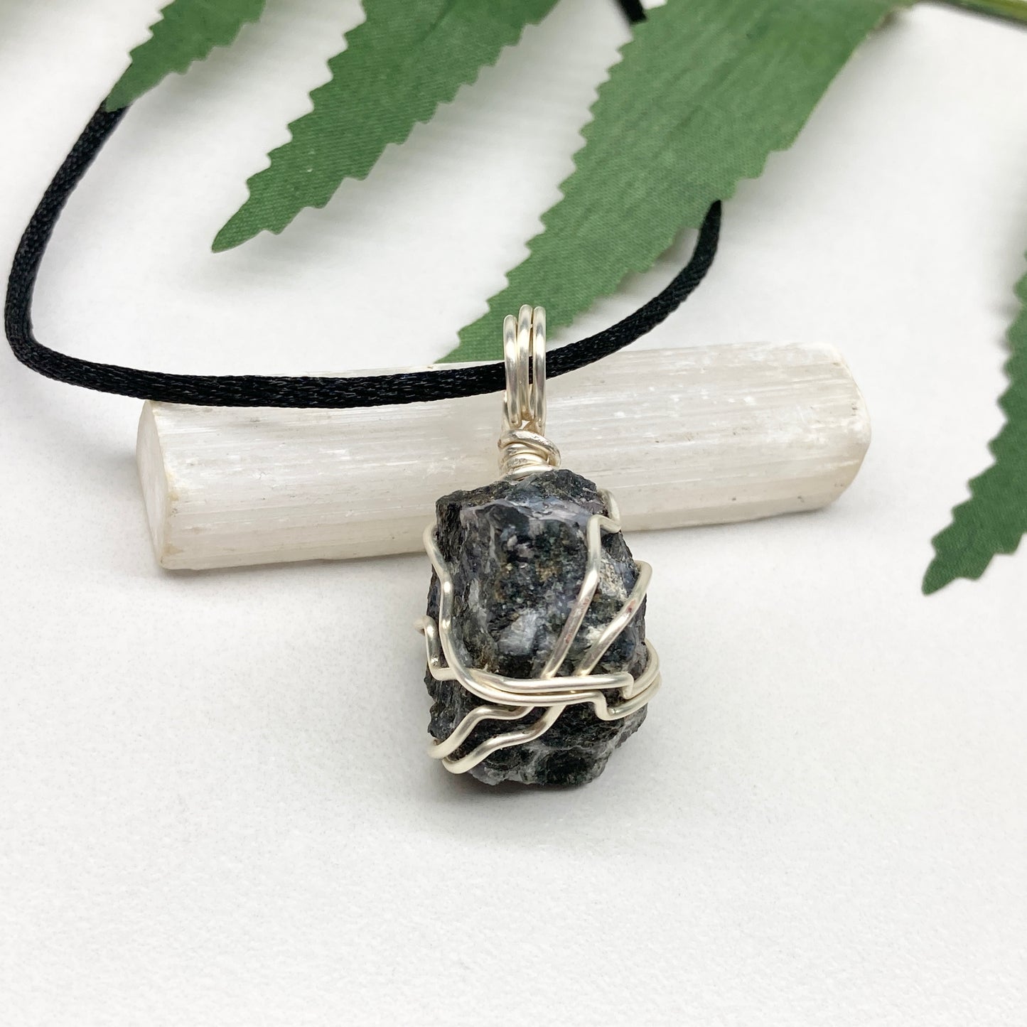 Indigo Gabbro necklace. Raw Indigo Gabbro stone wrapped with tarnish resistant wire. Hangs on a black chain. Also known as Mystic Merlinite. Gray and black marbled crystal.