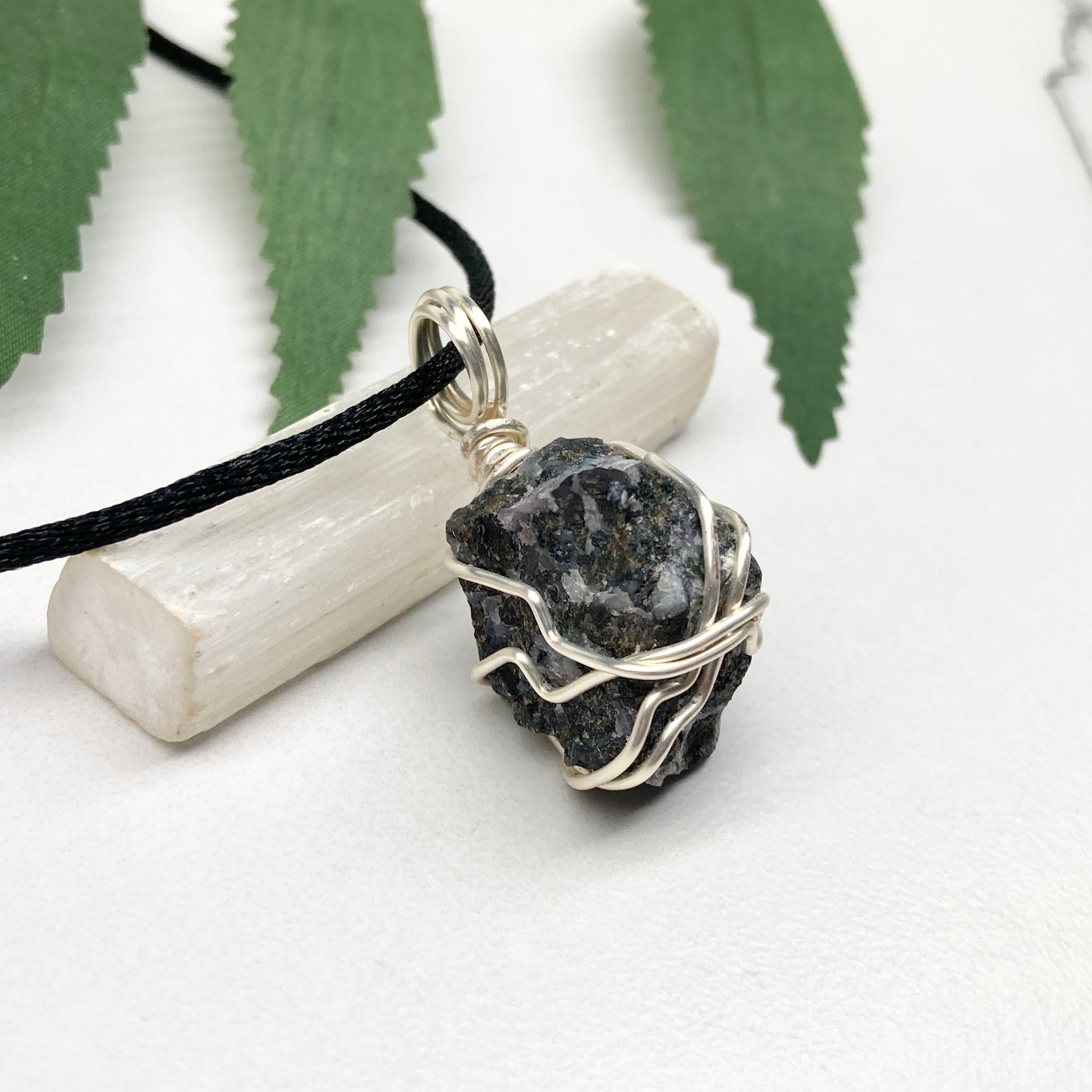 Indigo Gabbro necklace. Raw Indigo Gabbro stone wrapped with tarnish resistant wire. Hangs on a black chain. Also known as Mystic Merlinite. Gray and black marbled crystal.