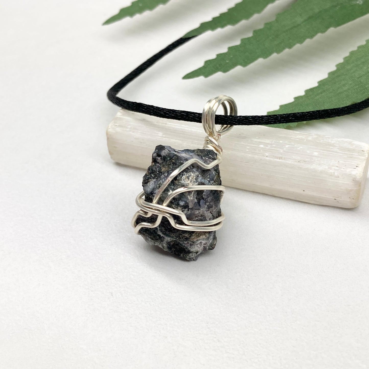 Indigo Gabbro necklace. Raw Indigo Gabbro stone wrapped with tarnish resistant wire. Hangs on a black chain. Also known as Mystic Merlinite. Gray and black marbled crystal.